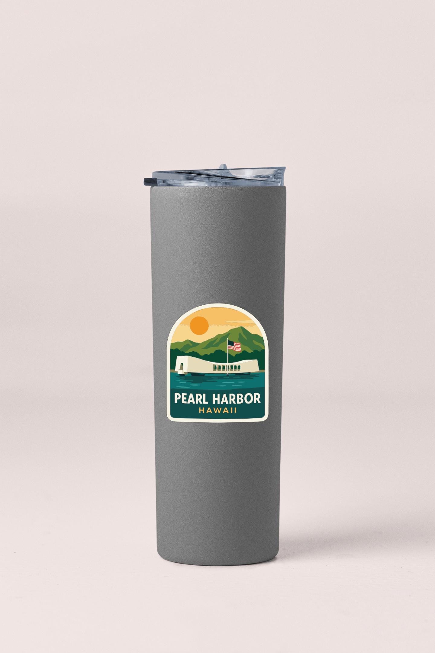 A gray insulated tumbler with a label that says "PEARL HARBOR HAWAII" and features an illustration of the Pearl Harbor memorial.