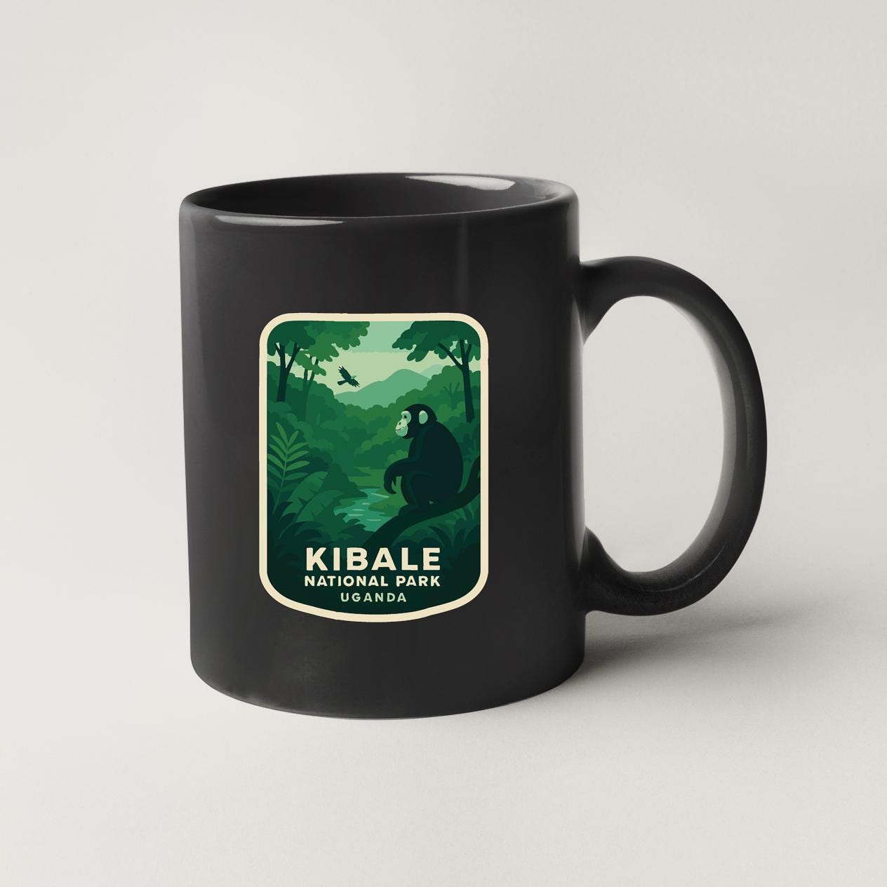A black coffee mug with a graphic design depicting a lush, green forest scene and the text "Kibale National Park Uganda".