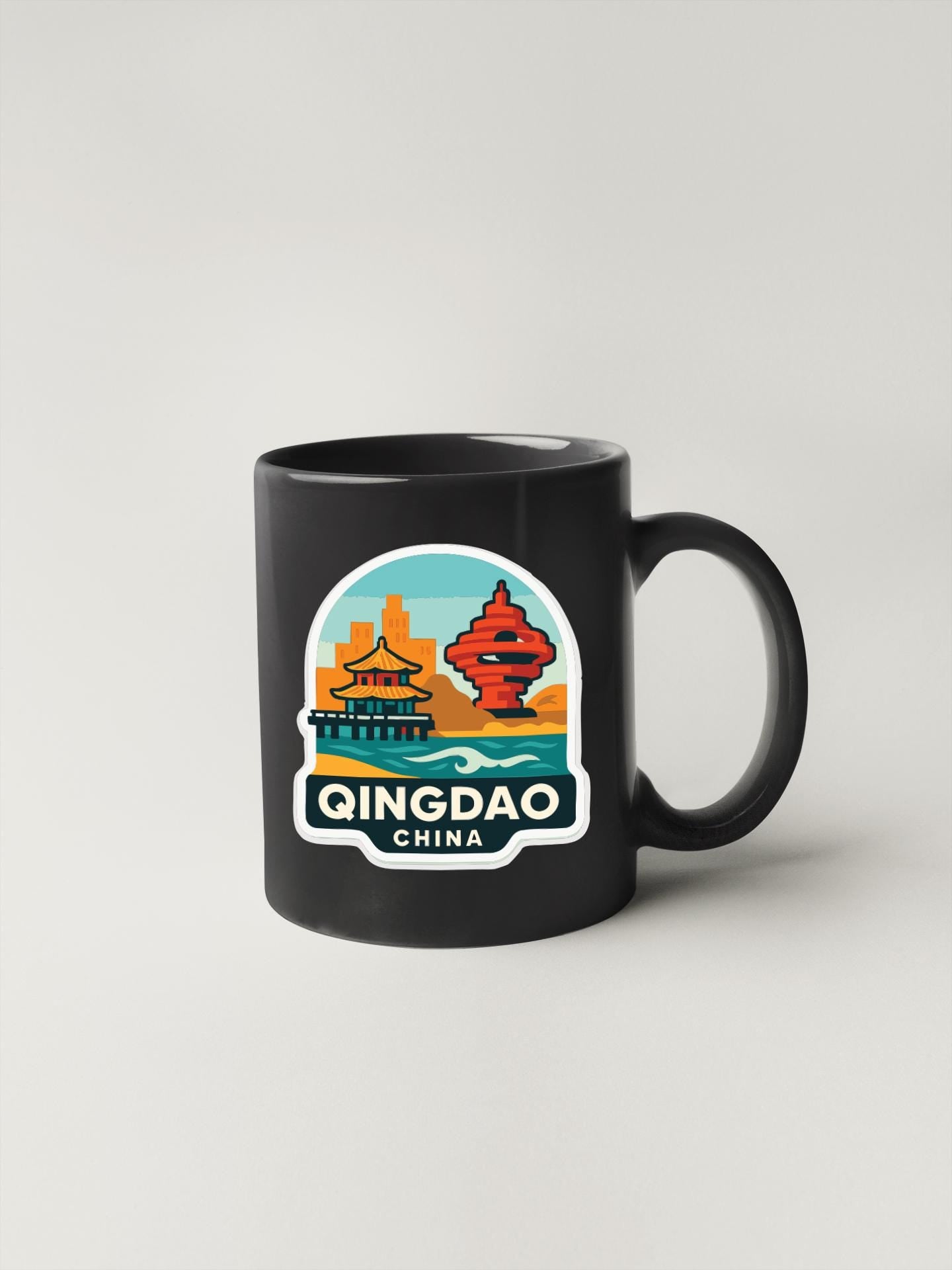 A black coffee mug with a sticker depicting landmarks and buildings in Qingdao, China.