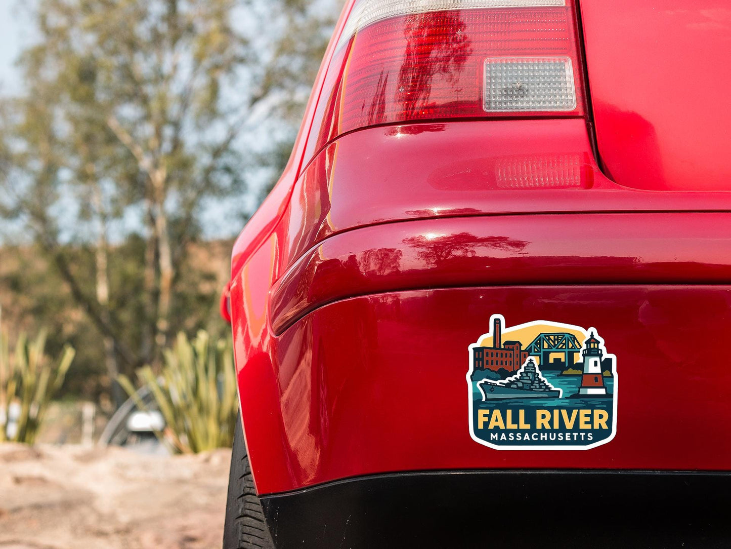 the rear end of a red car with a sticker on the trunk that says "FALL RIVER MASSACHUSETTS".