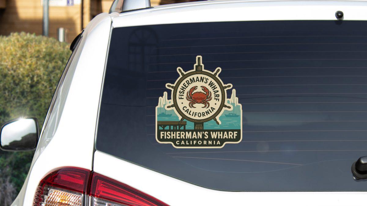a sticker on the rear window of a white vehicle, displaying the name "Fisherman's Wharf" and the location "California" along with a crab symbol.