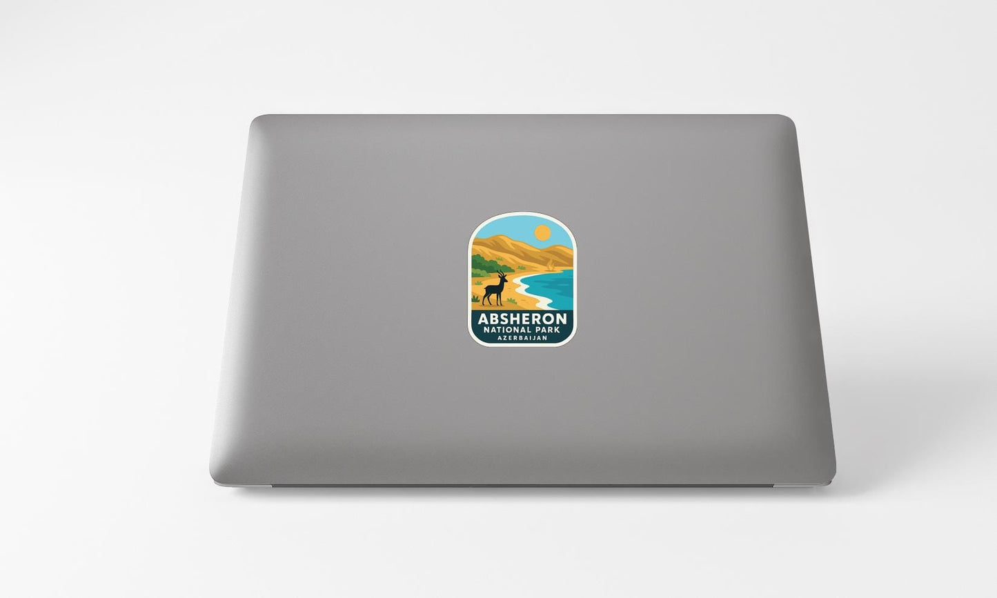A sticker on the back of a laptop displaying a scenic landscape with mountains, a beach, and a dog.