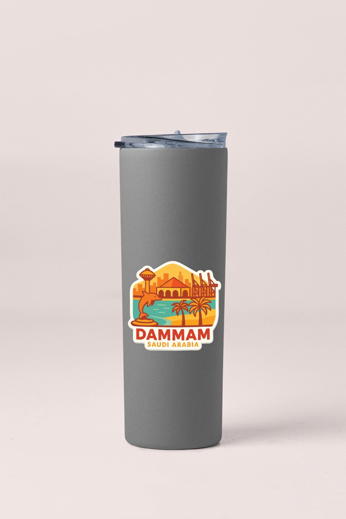 A gray insulated tumbler with a sticker depicting a cityscape and the text "DAMMAM SAUDI ARABIA".