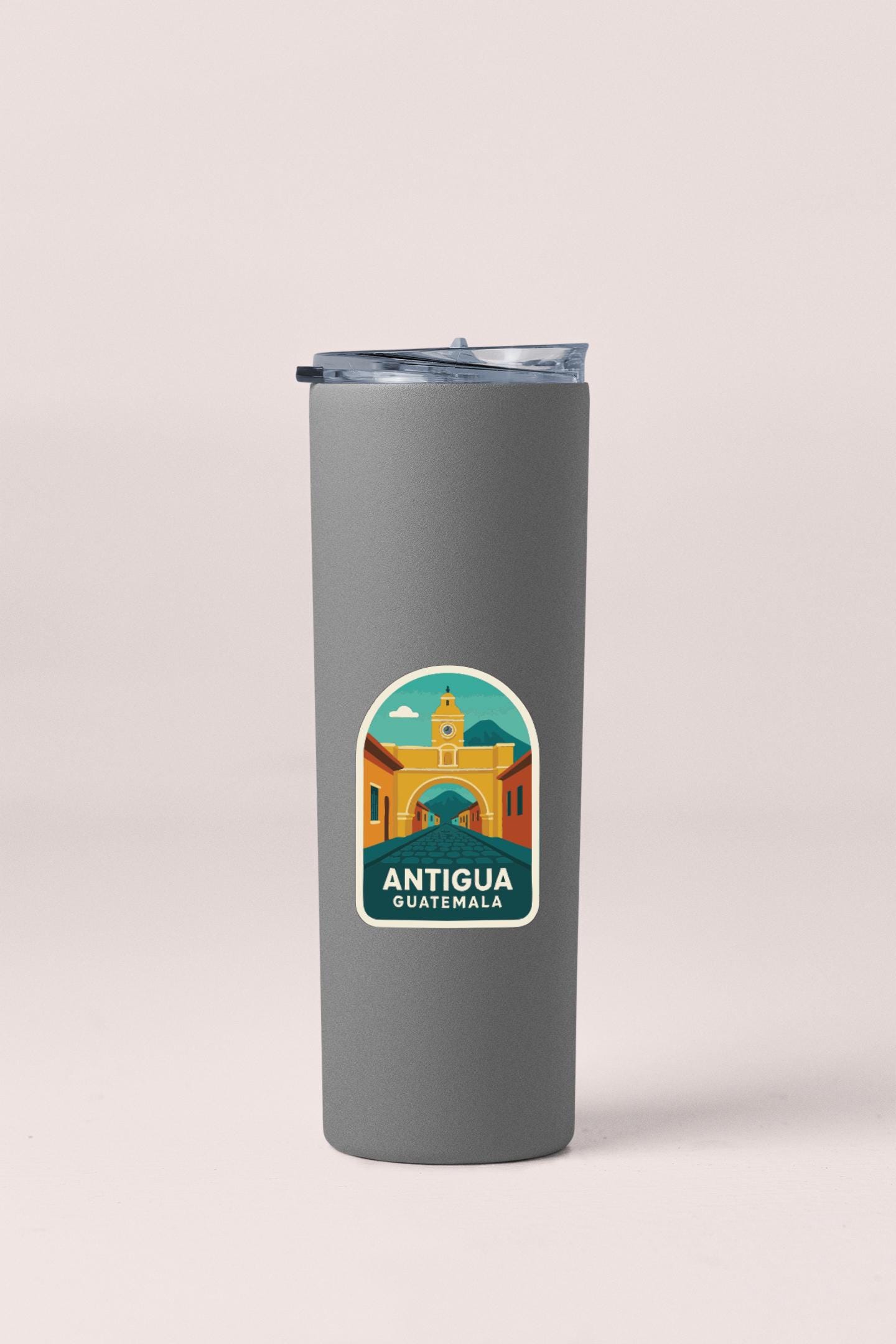 A gray insulated tumbler with a sticker depicting the Antigua Guatemala cityscape.