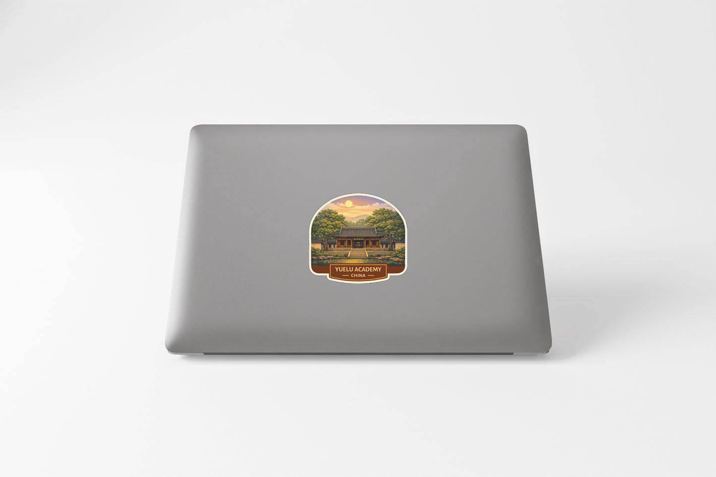 A sticker on the back of a laptop, depicting a scenic landscape with a building in the background.