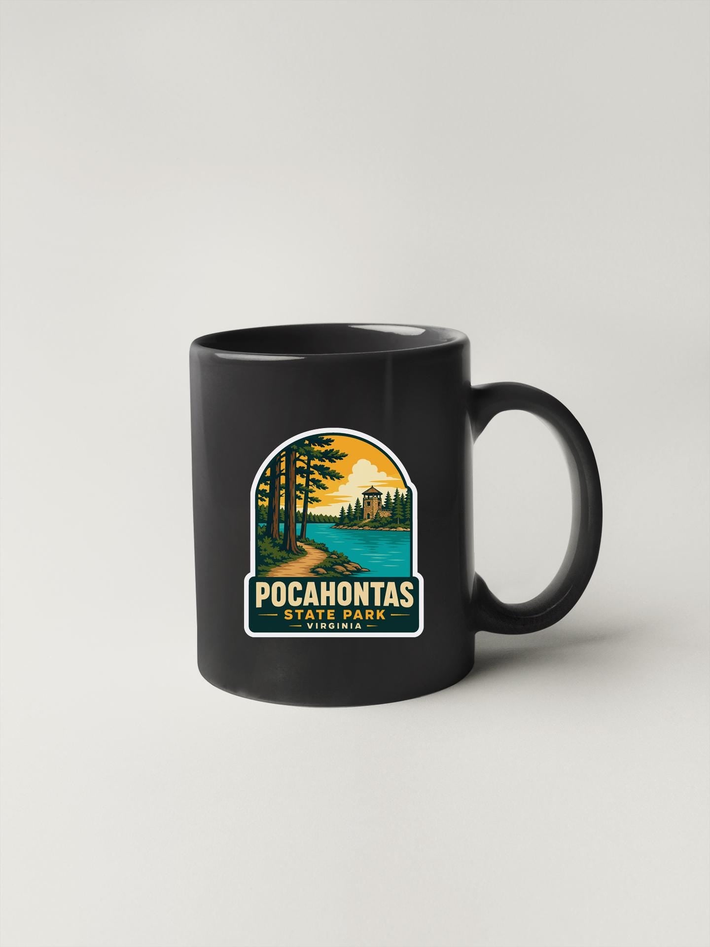 A black coffee mug with a sticker depicting a scenic landscape featuring a lake, trees, and mountains.