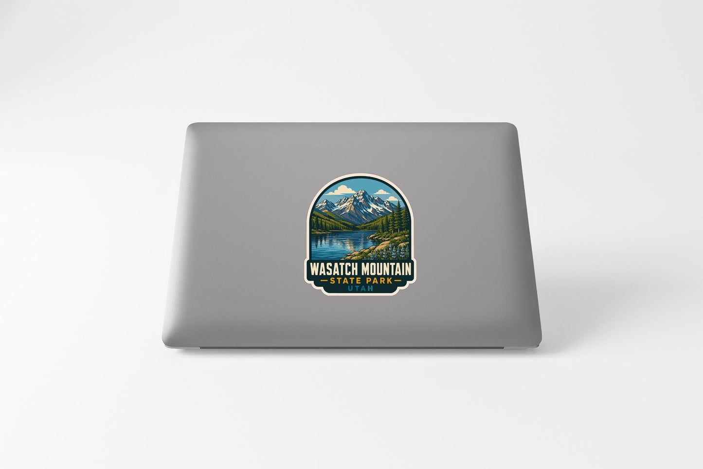 A sticker on the back of a laptop that features a scenic mountain landscape with a lake and mountains in the background.