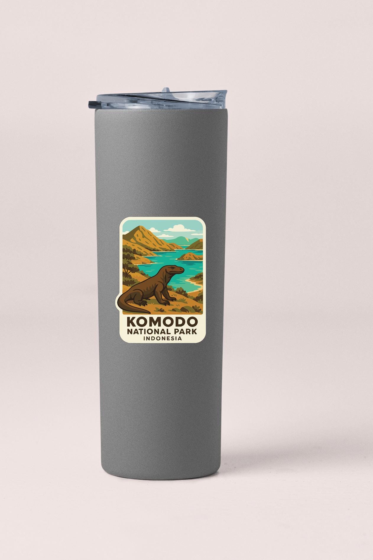 A gray insulated tumbler with a sticker depicting Komodo National Park in Indonesia.