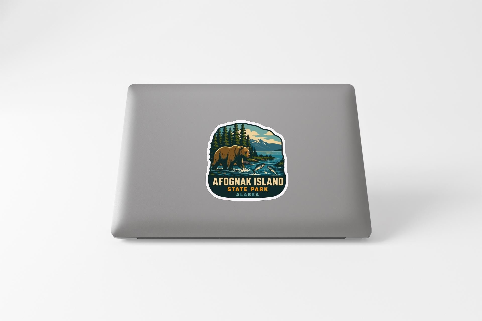 a sticker on a laptop that depicts a bear in a forest setting, with the text "AFOGNAK ISLAND" and "ALASKA" printed on it.