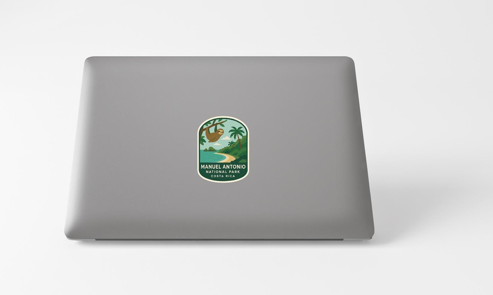 A sticker on the back of a laptop, depicting a tropical landscape with palm trees and a beach.