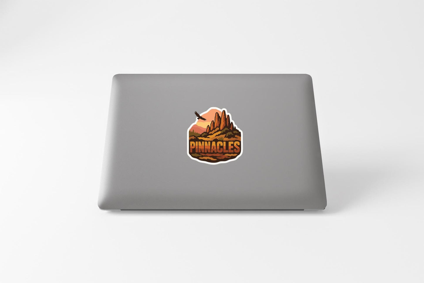 a sticker with a mountain landscape and the word "PINNACLES" on the back of a laptop.