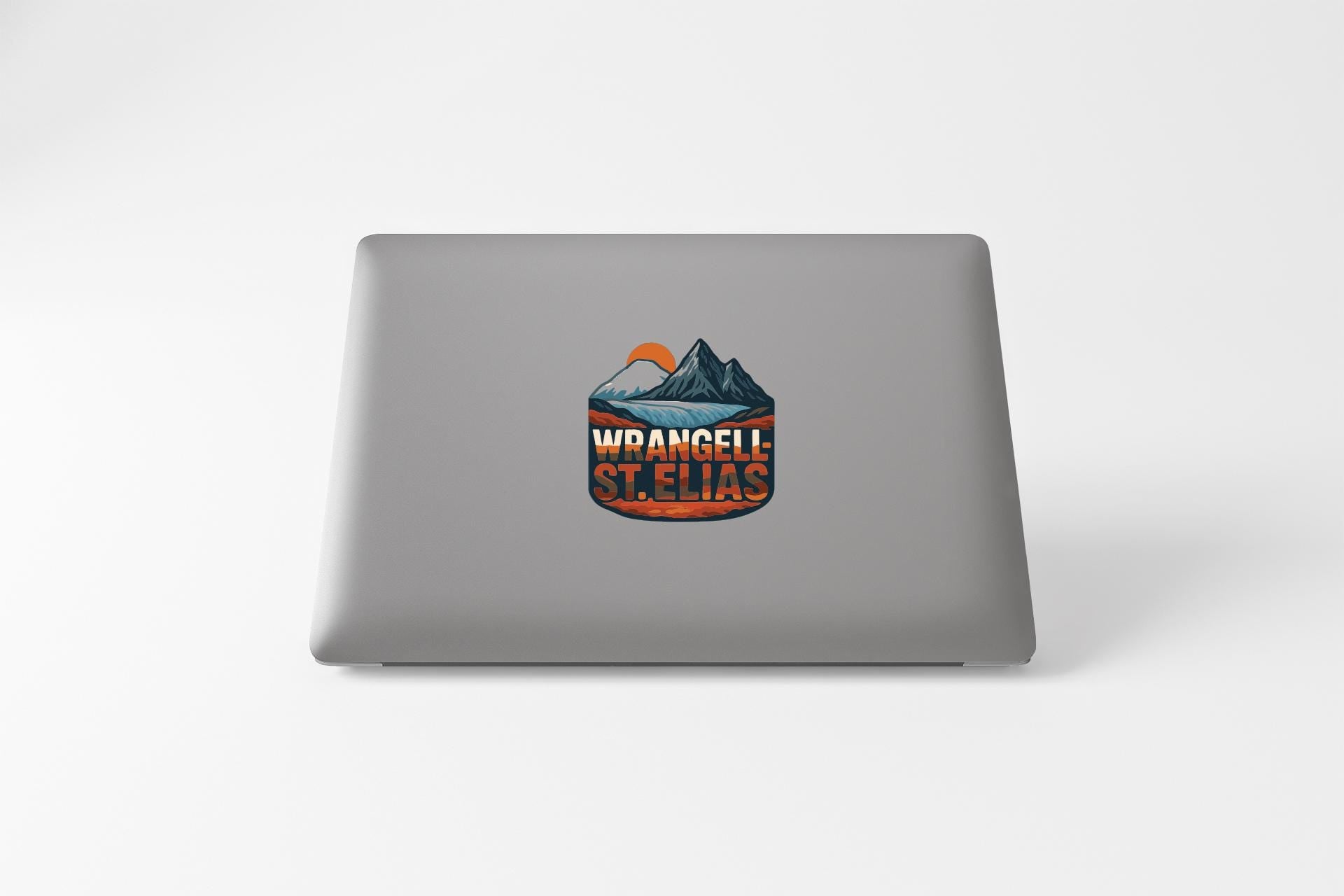 a sticker on the back of a laptop with a mountain landscape and the text "WRANGEL STELIAS" printed on it.