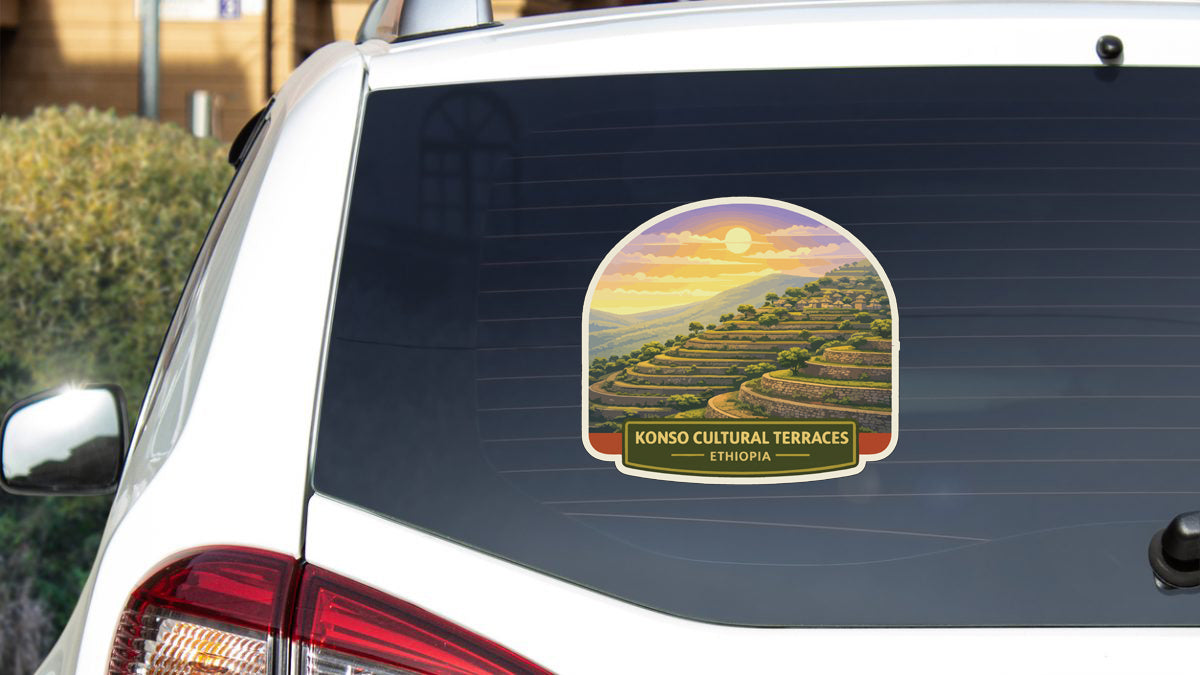 a sticker on the rear window of a car, depicting a scenic landscape with hills and a sunset.