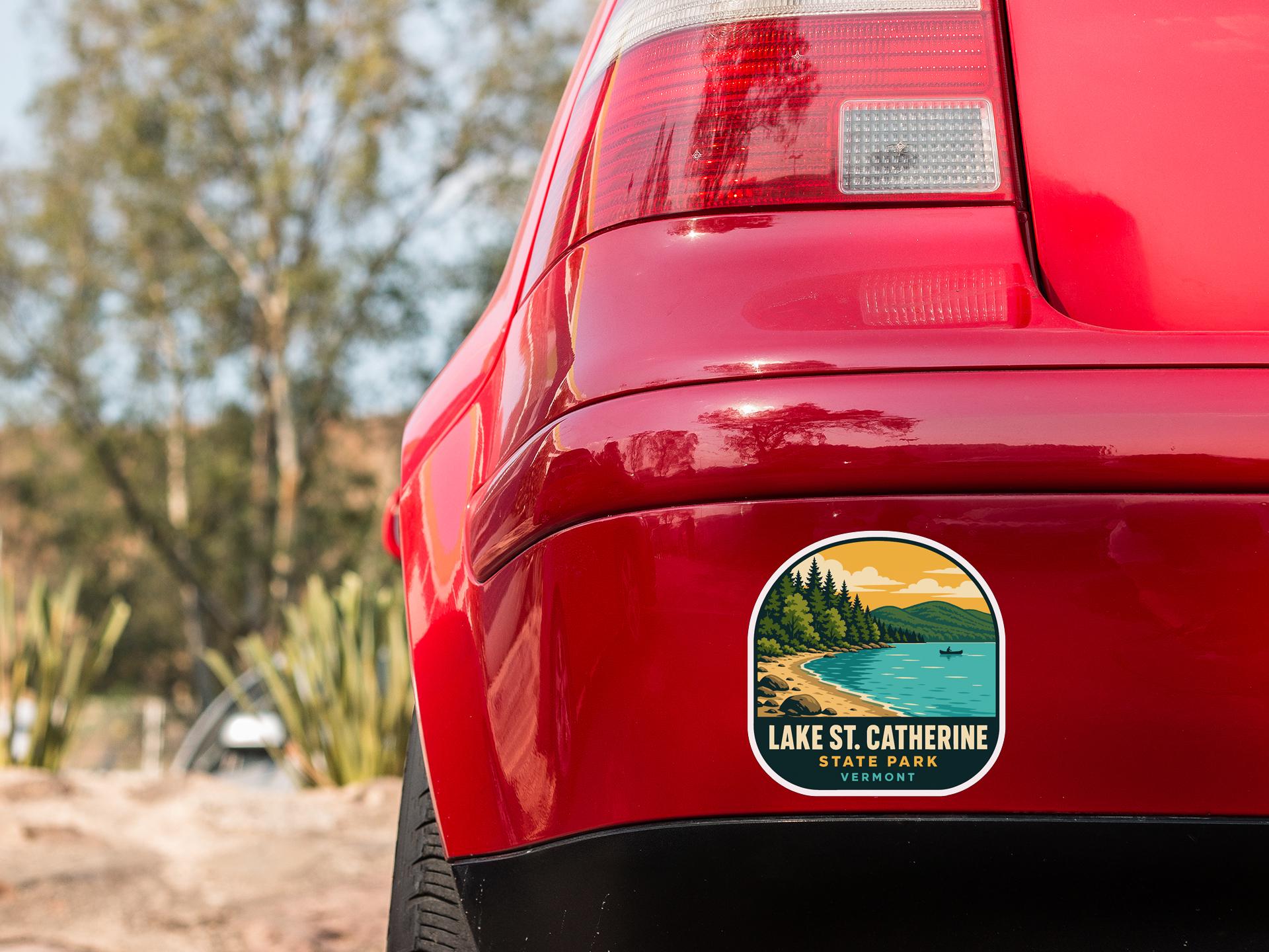 the rear end of a red car with a sticker on the back window that reads "Lake St. Catherine State Park, Vermont".