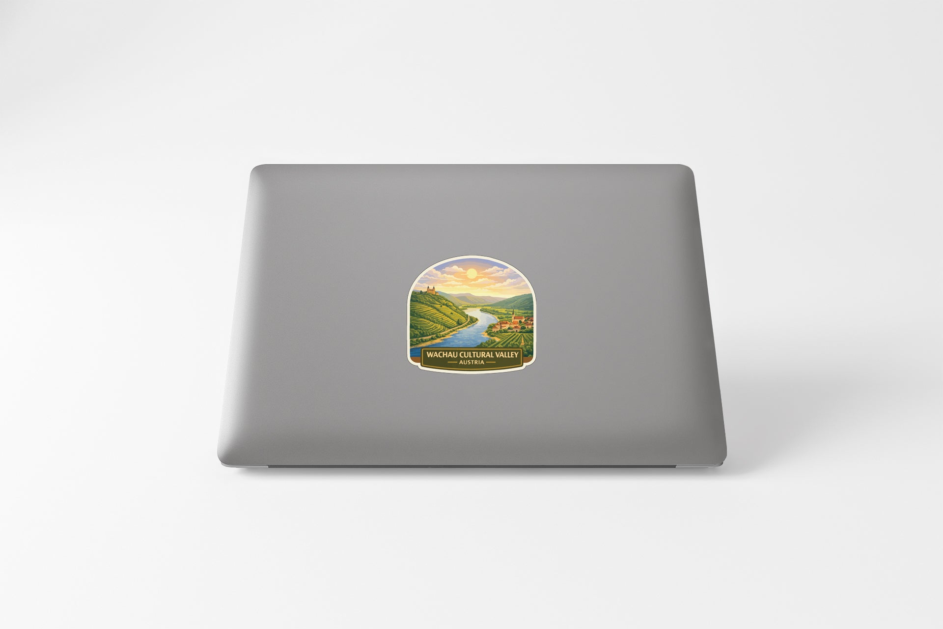 A sticker depicting a scenic landscape with a river and mountains, placed on the back of a laptop computer.