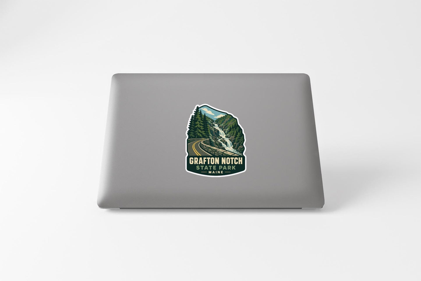 A sticker on the back of a laptop, depicting a scenic mountain landscape with a waterfall.
