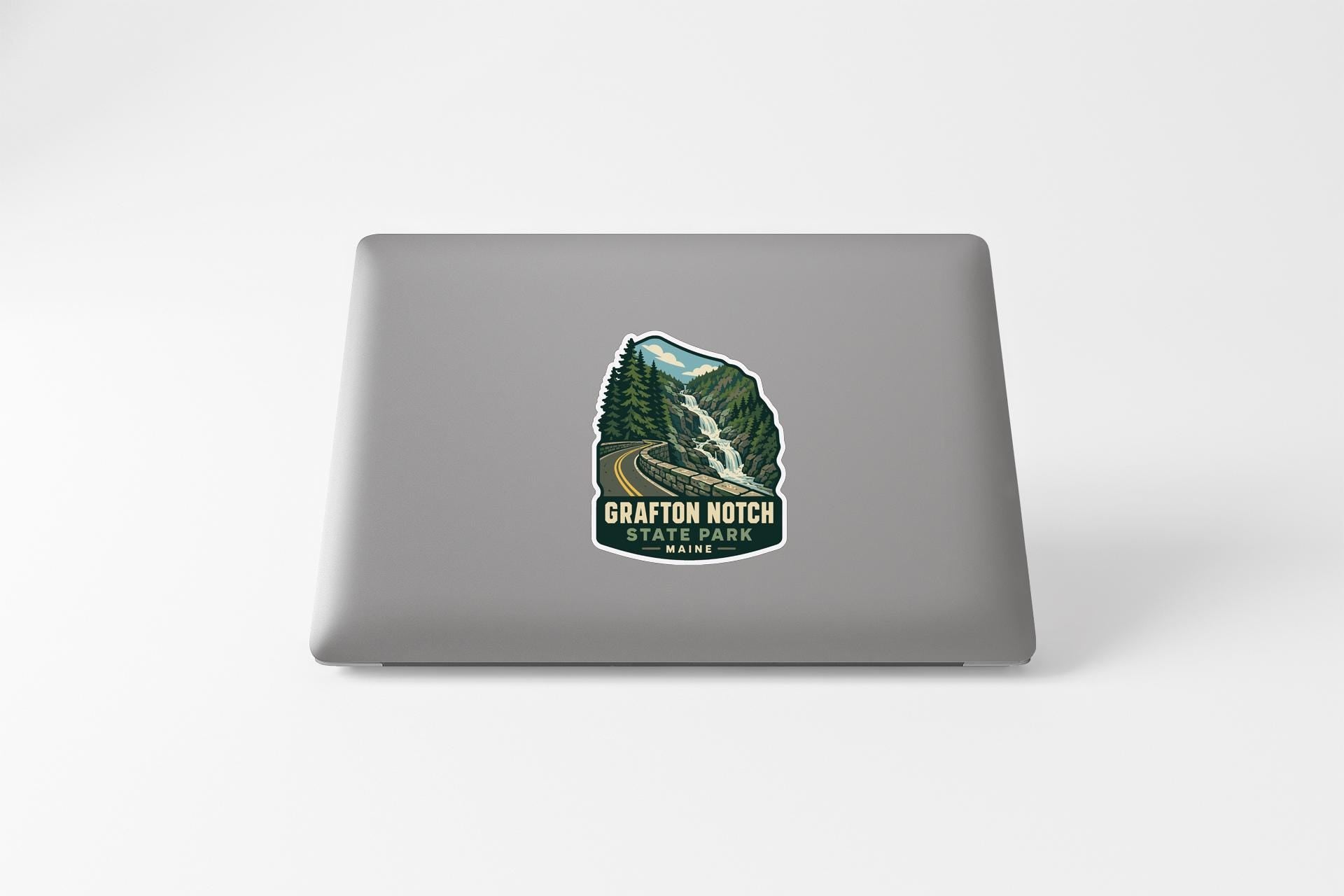 A sticker on the back of a laptop, depicting a scenic mountain landscape with a waterfall.