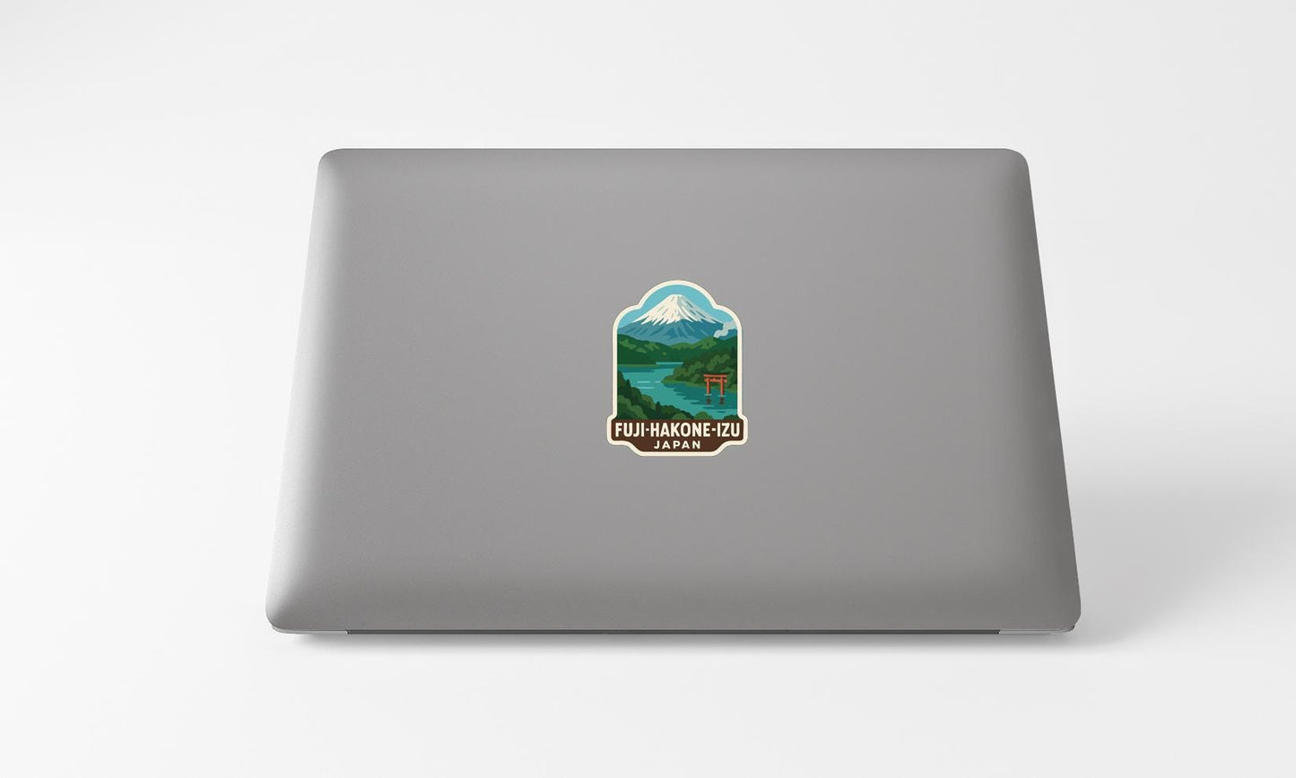 A sticker on the back of a laptop, depicting a mountain landscape with a river and a temple.
