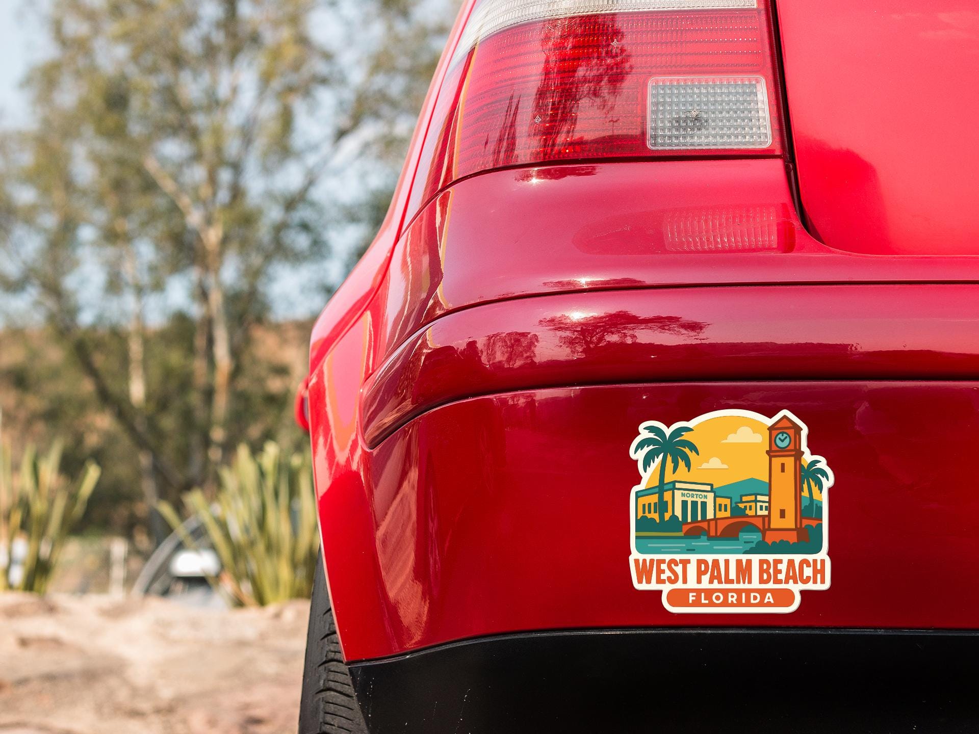the rear end of a red car with a sticker on the back window that says "West Palm Beach, Florida".