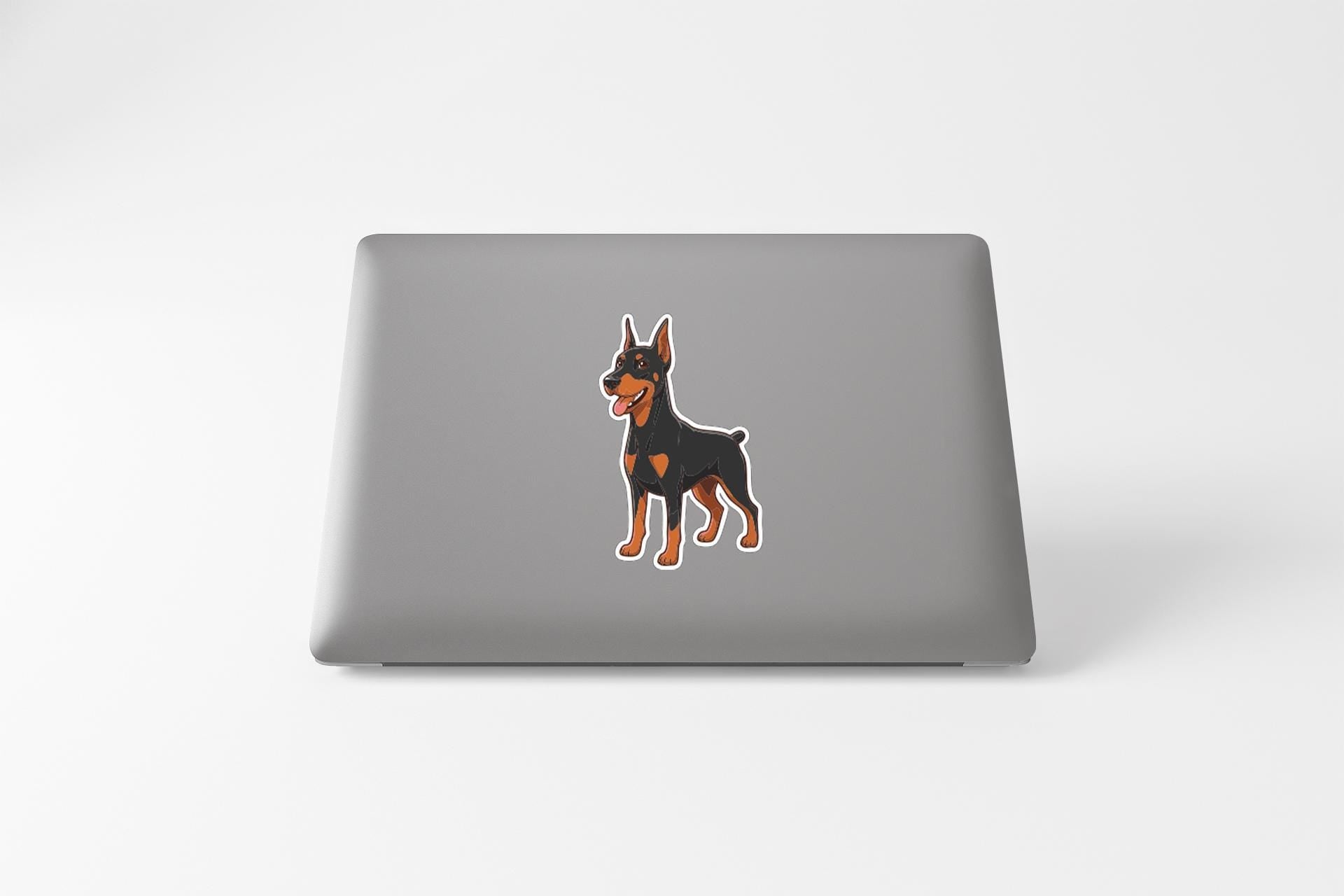 A sticker of a Doberman Pinscher dog is displayed on the back of a laptop computer.