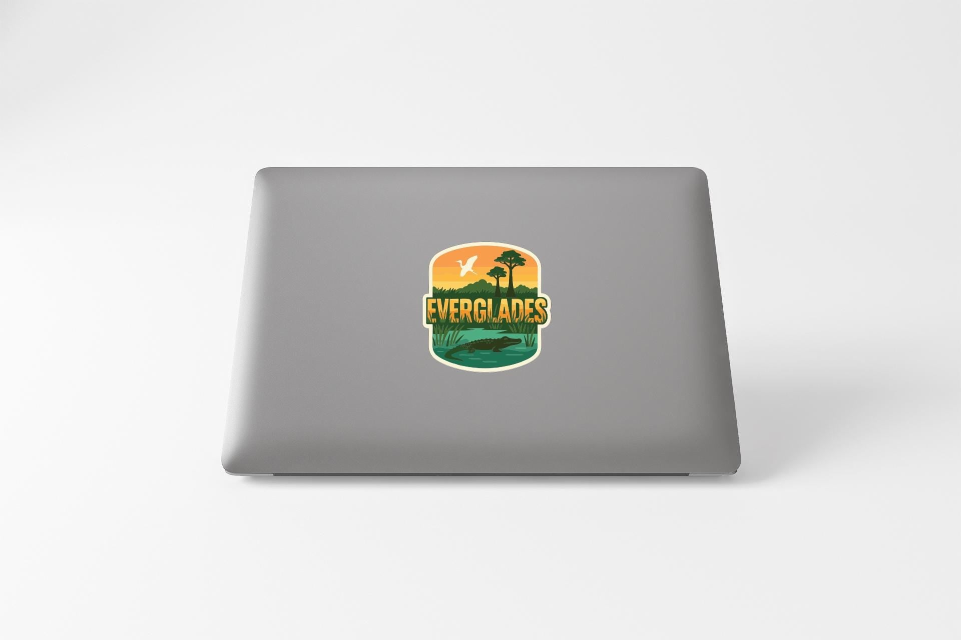 a sticker with a tropical landscape and the word "EVERGLADES" printed on a grey laptop.