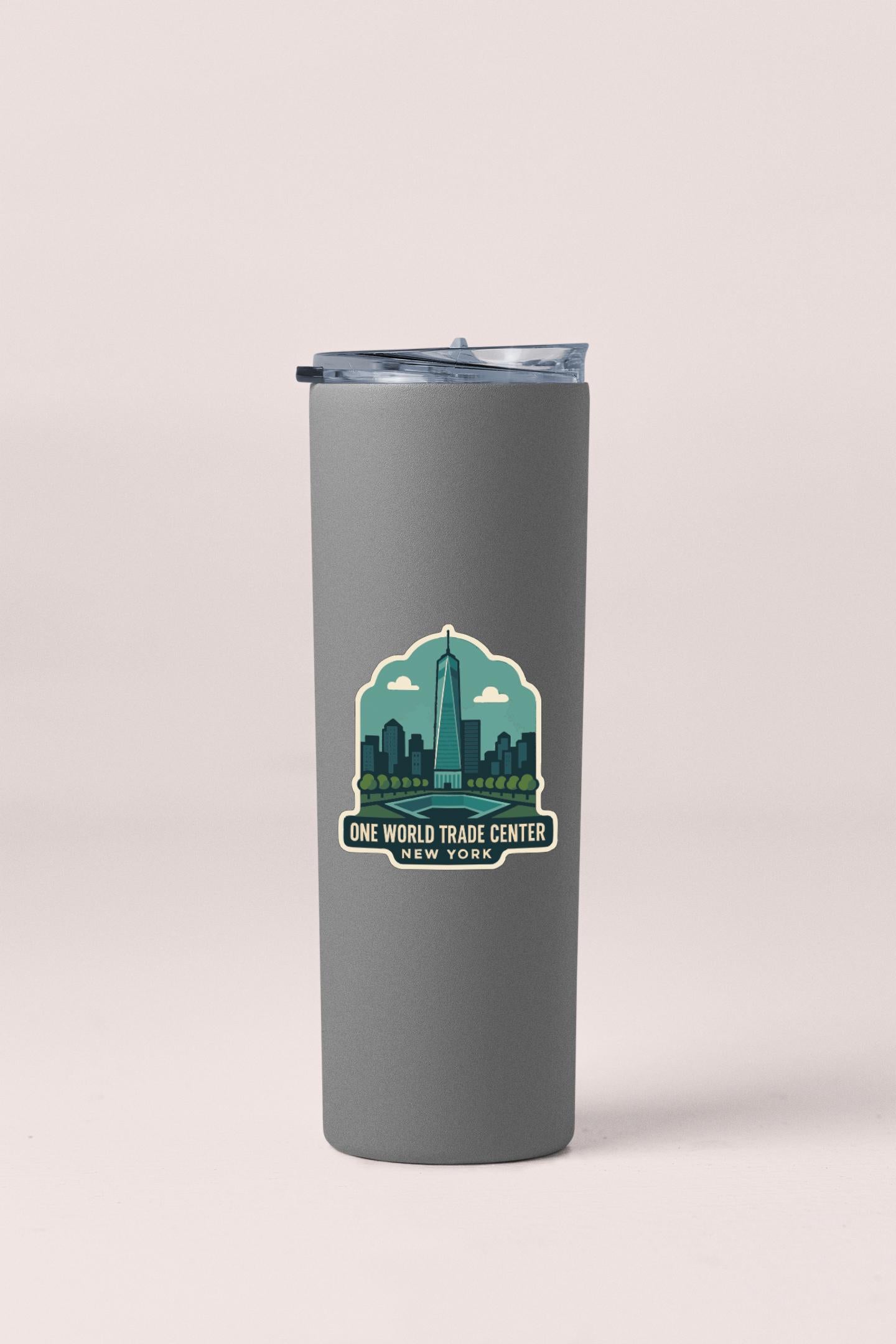 A gray tumbler with a lid and a sticker depicting the One World Trade Center in New York.