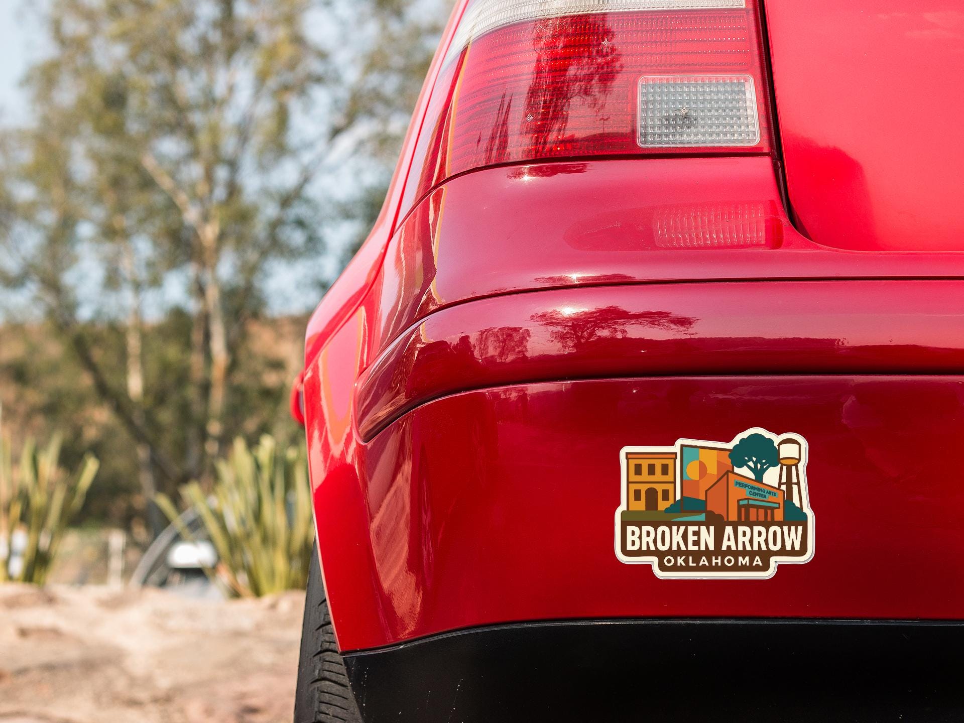 the rear end of a red car with a sticker on the trunk that says "Broken Arrow Oklahoma".