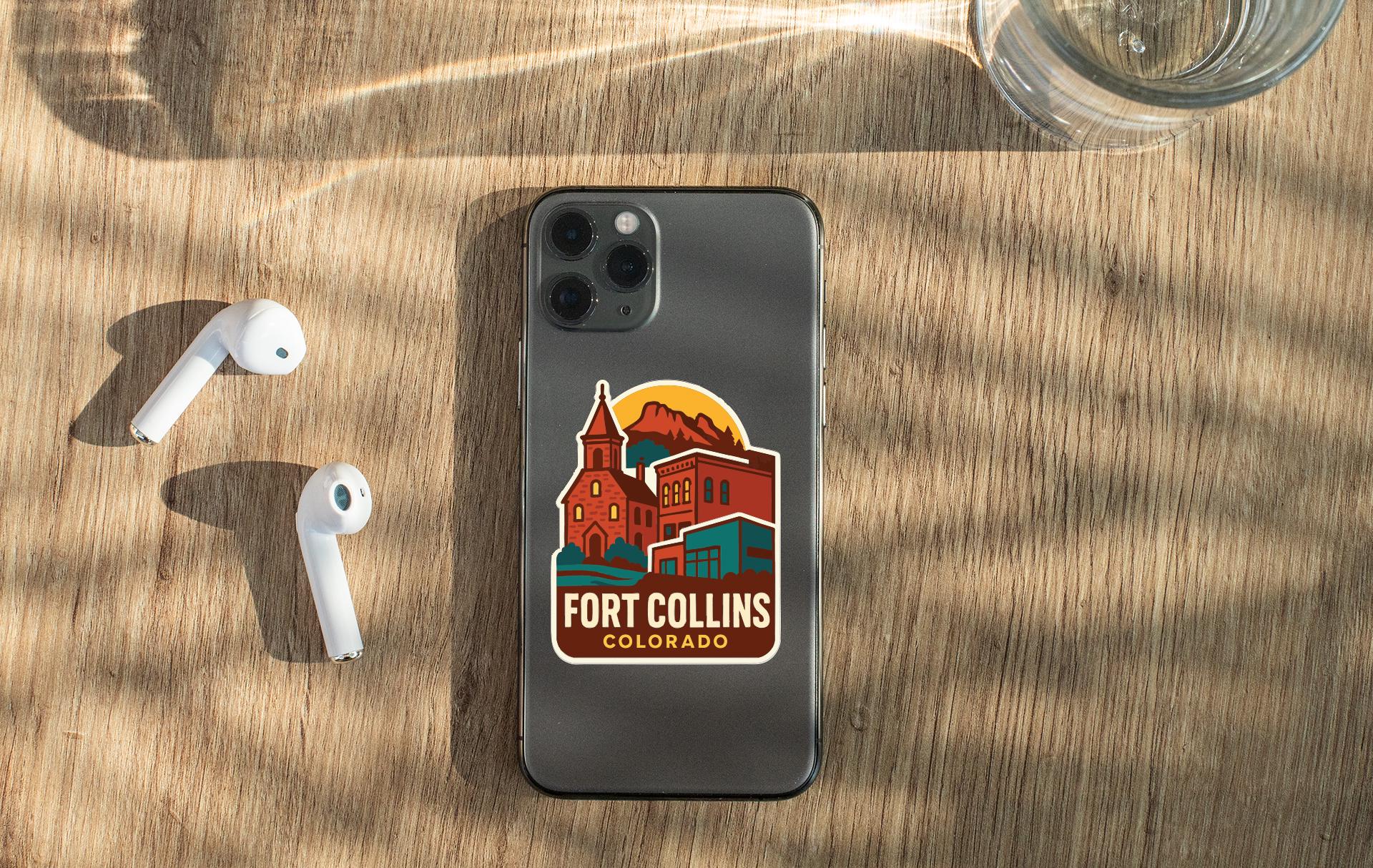 a smartphone with a sticker on the back, placed on a wooden surface alongside a pair of white earbuds and a glass of water.