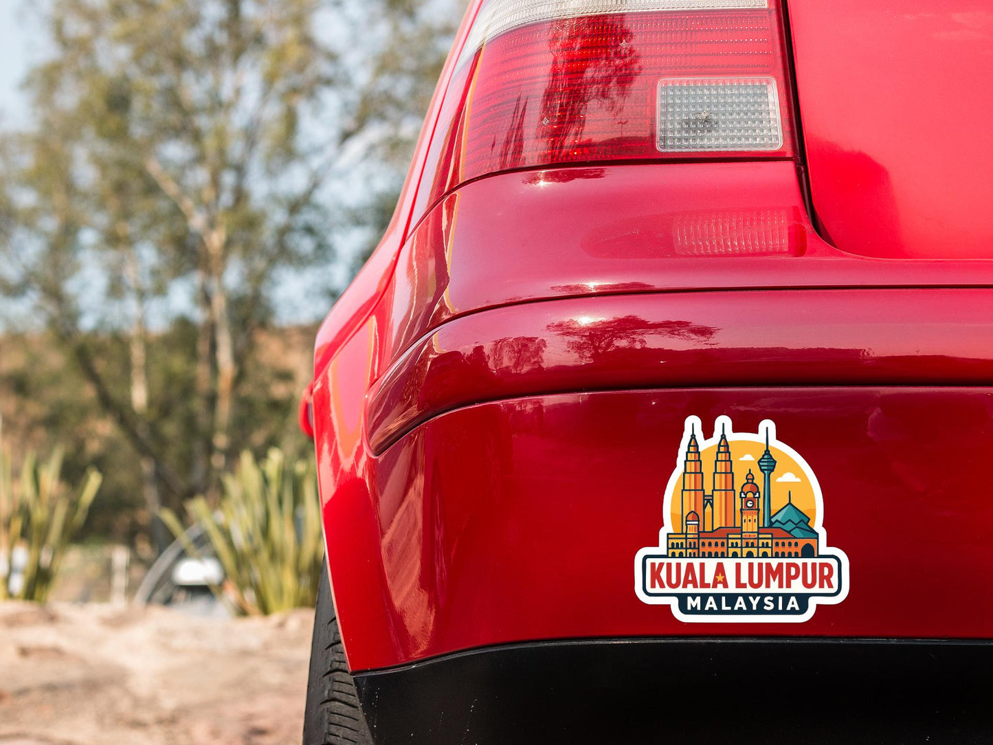 the rear end of a red car with a sticker on the trunk that says " Kuala Lumpur Malaysia".