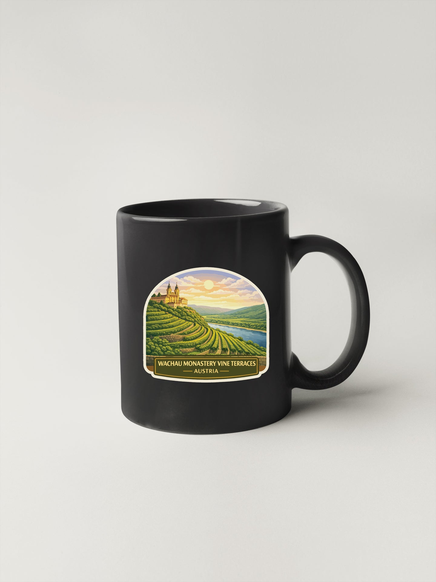 A black coffee mug with a label depicting a scenic landscape, including vineyards and a sunset.