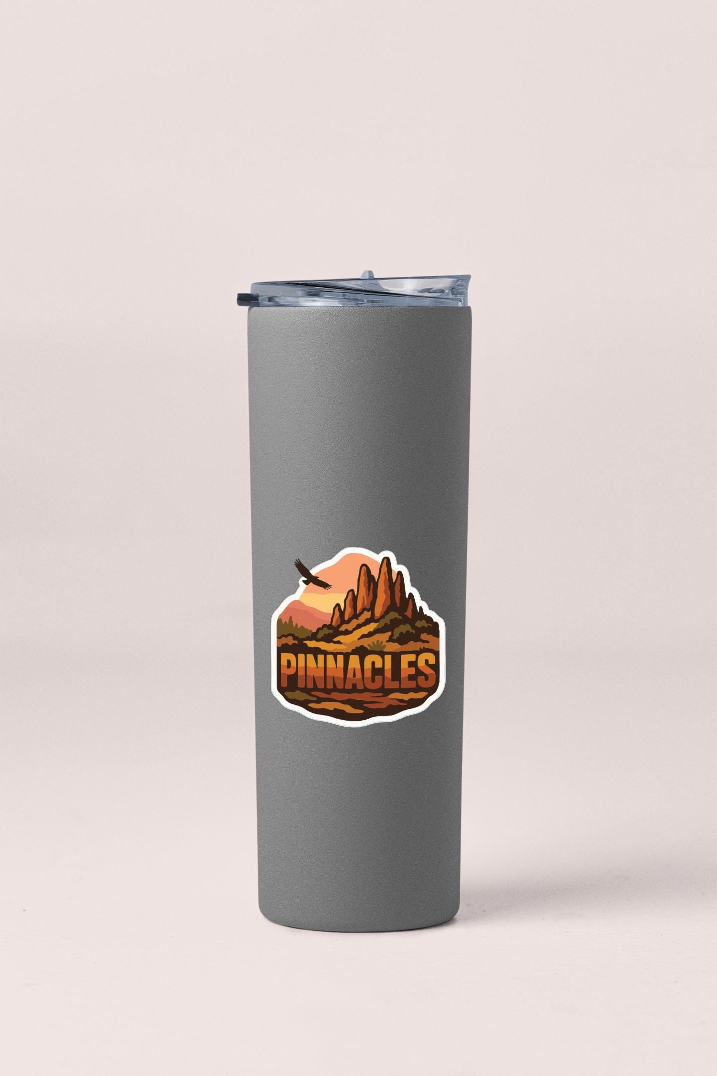 A gray insulated tumbler with a logo depicting a mountain landscape.