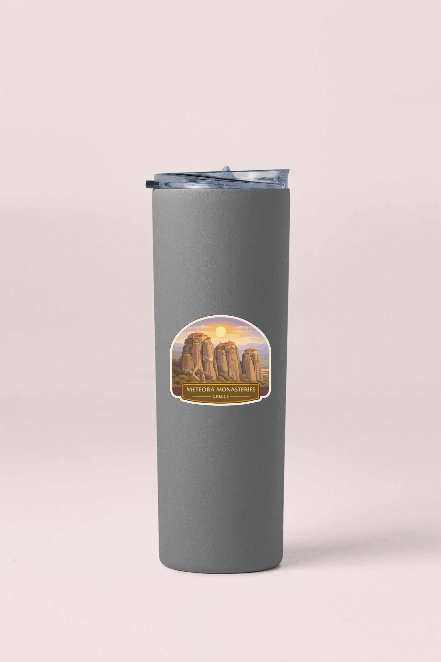 A gray tumbler with a label featuring a scenic mountain landscape.