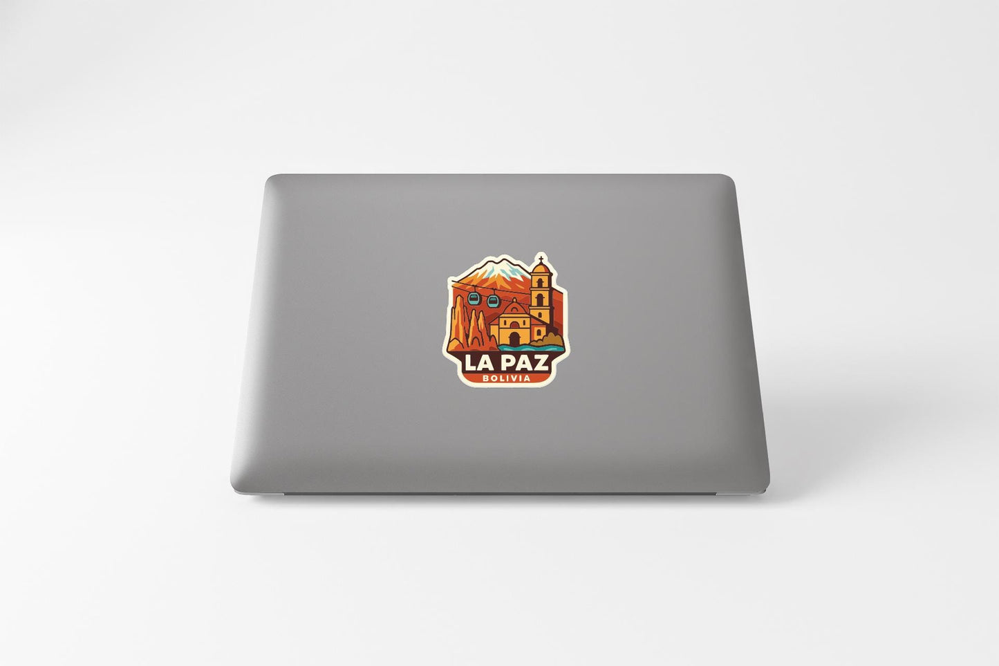 A sticker on the back of a laptop, depicting a colorful illustration of a building with a mountain in the background.