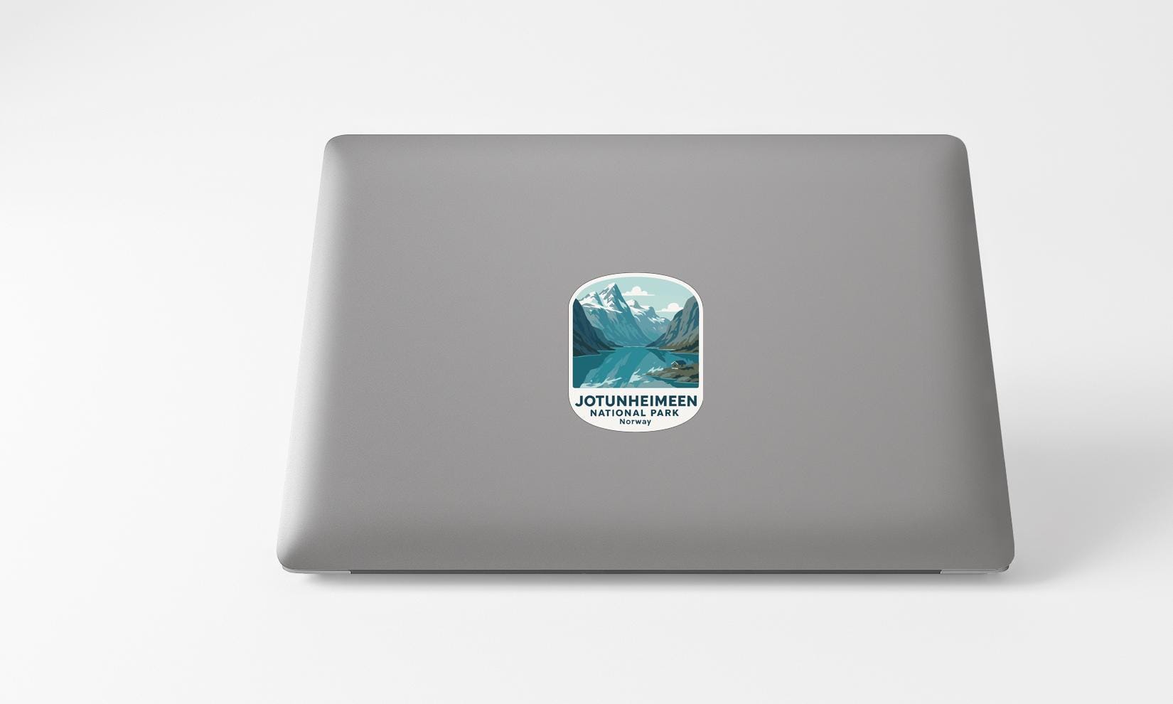 A sticker on the back of a laptop displaying a mountain landscape with a lake.