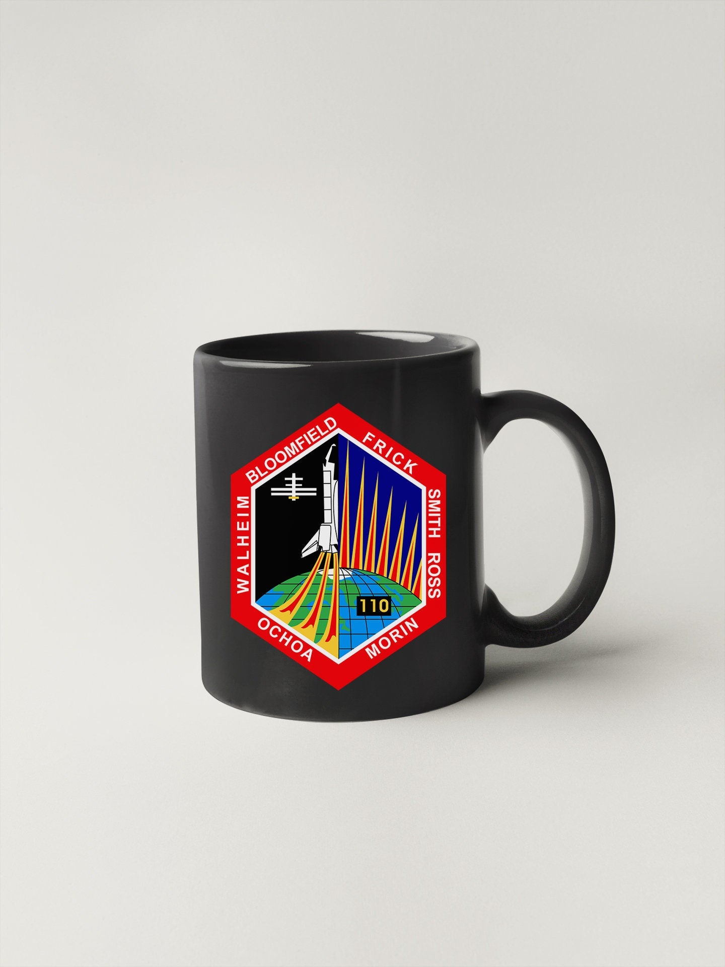 a black coffee mug with a space shuttle on it