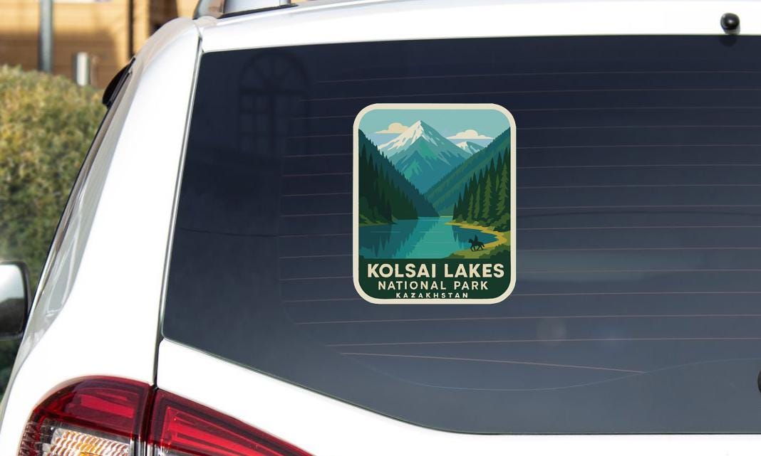 A sticker on the rear window of a car that says "Kolsai Lakes National Park" and features a scenic mountain landscape.