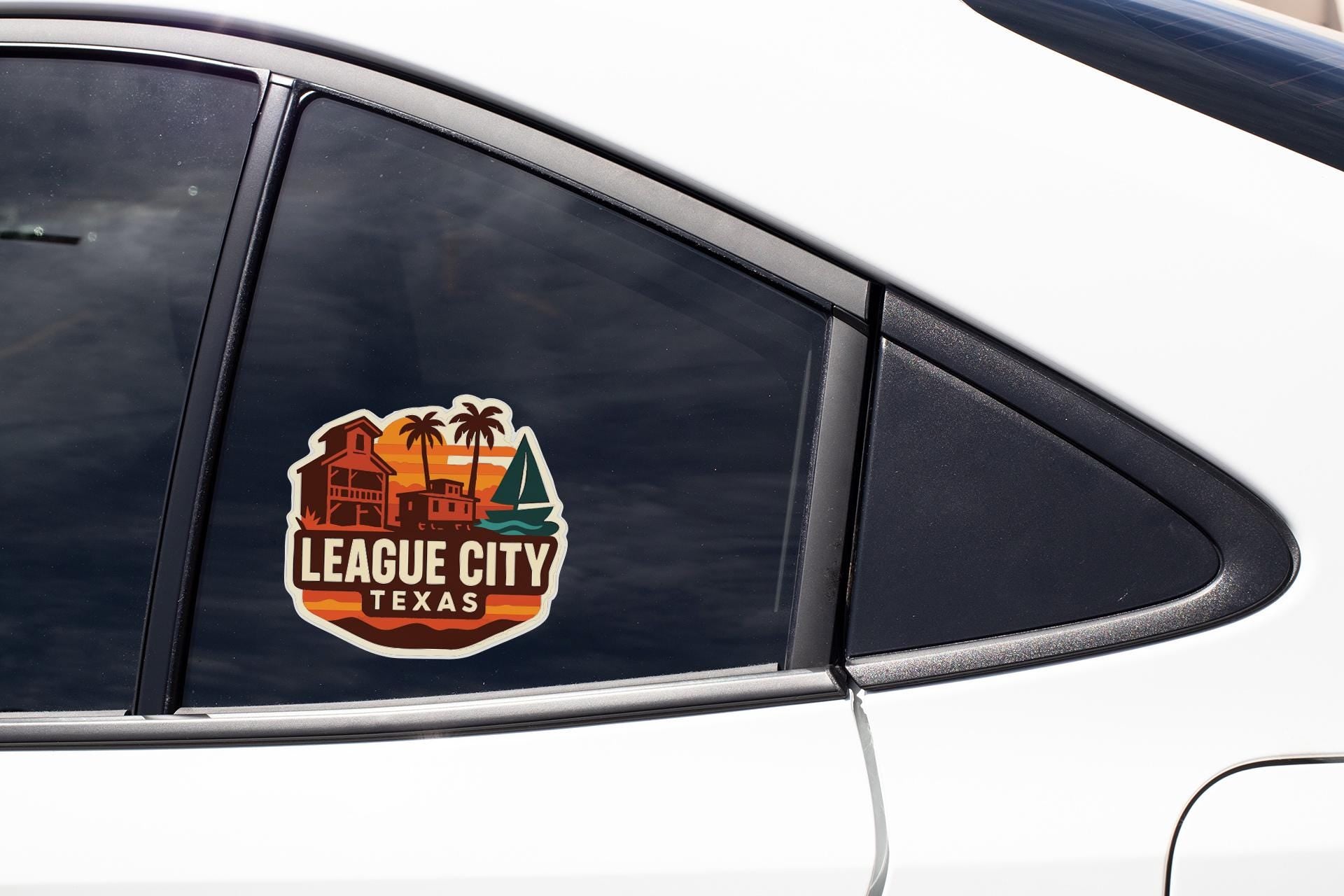 A sticker on the side of a car window that says "LEAGUE CITY TEXAS".