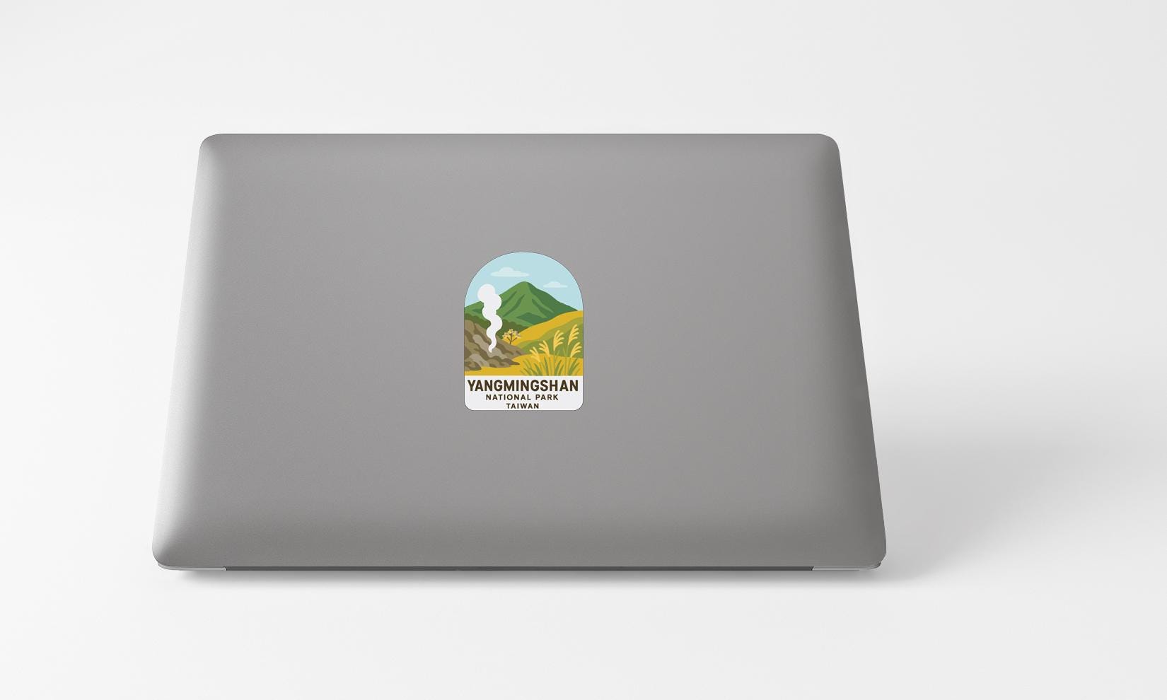 A sticker with a mountain landscape and text on the back of a laptop computer.
