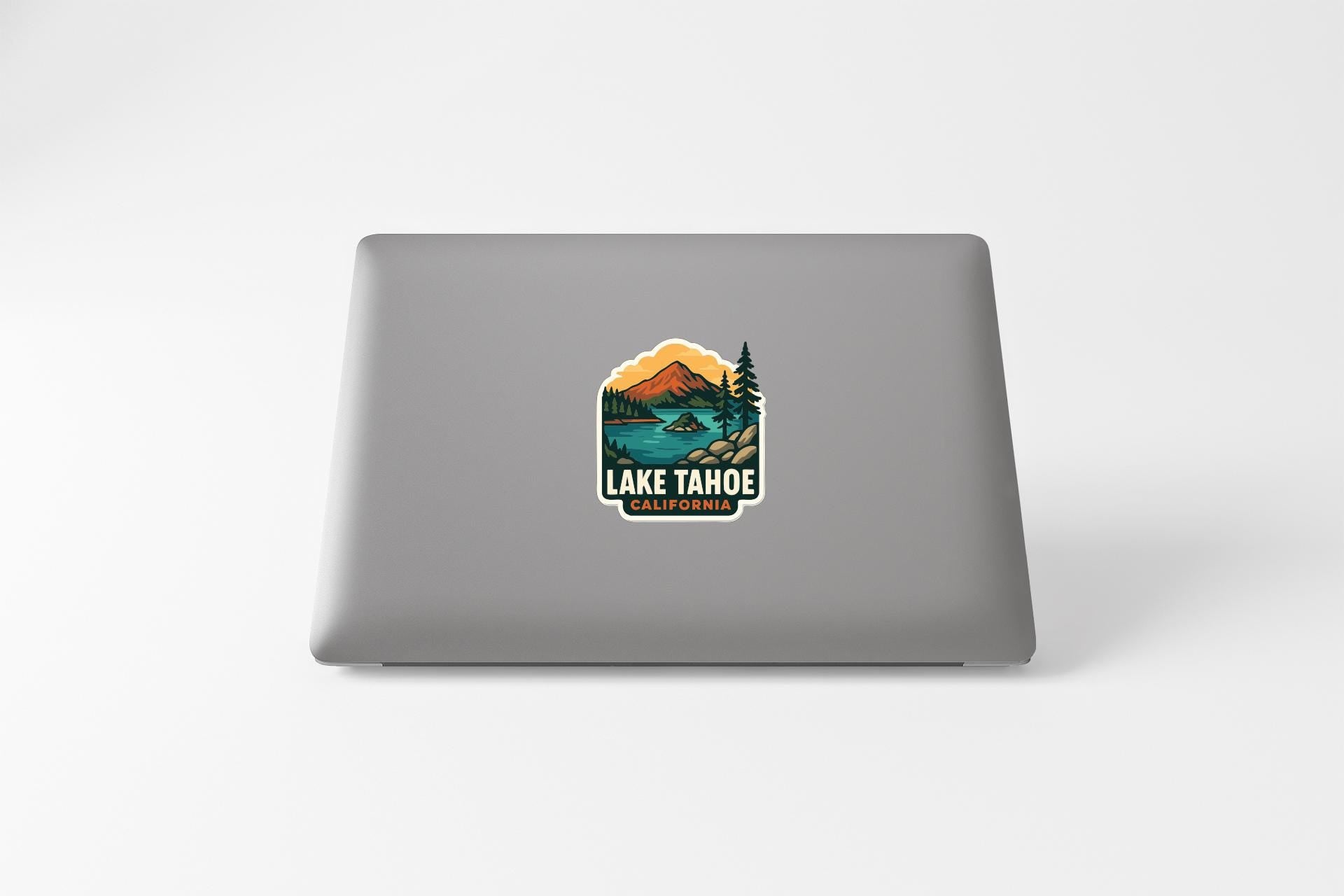 A sticker on the back of a laptop that features a scenic landscape with mountains, trees, and a lake, along with the text "LAKE TAHOE, CALIFORNIA".