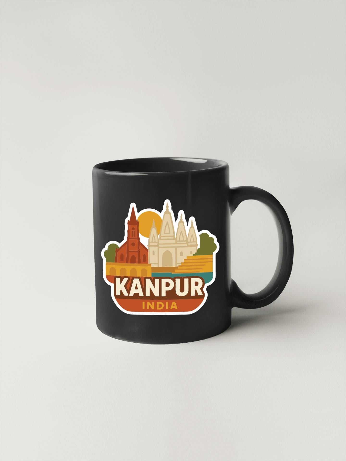 A black coffee mug with a colorful sticker depicting the skyline of Kanpur, India.