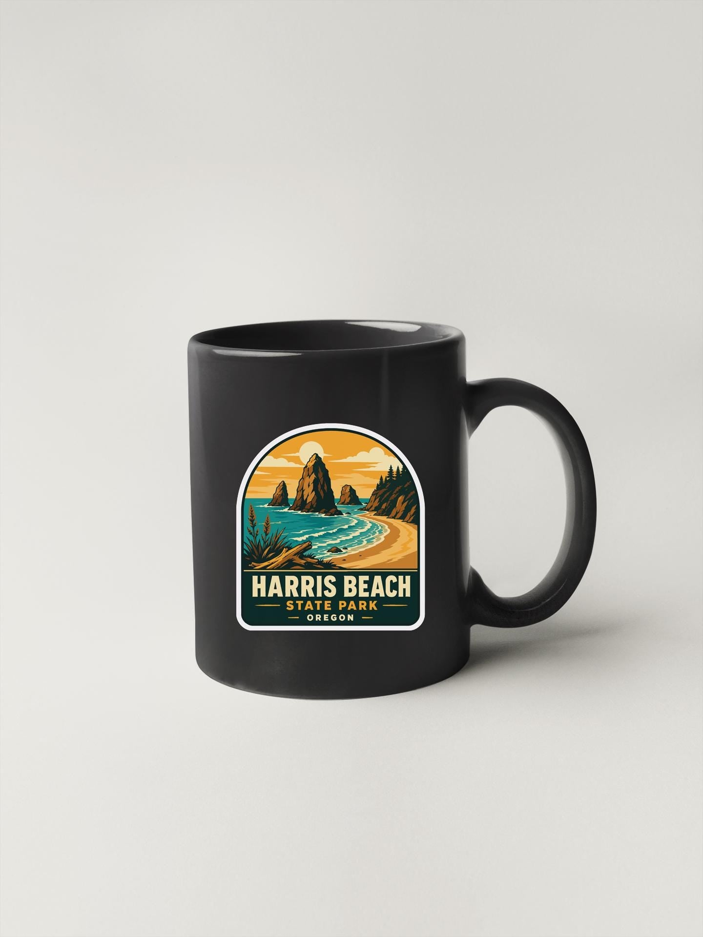 A black coffee mug with a graphic design depicting a scenic landscape, including mountains, a beach, and a body of water.