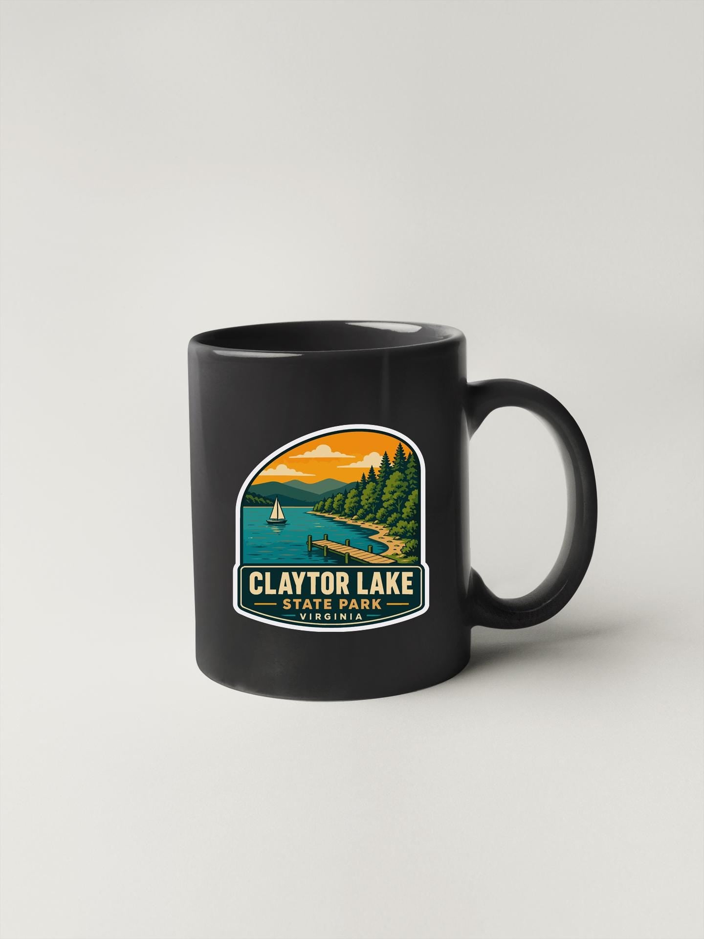 A black coffee mug with a sticker depicting a scenic lake and mountains.