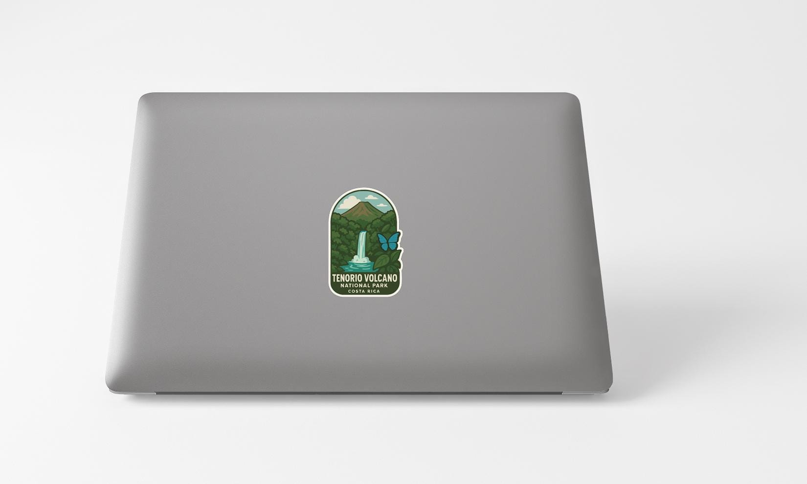 A sticker on the back of a laptop, depicting a waterfall and mountains, with the text "TENORO VOLCANO" and "TENORO VOLCANO" written on it.
