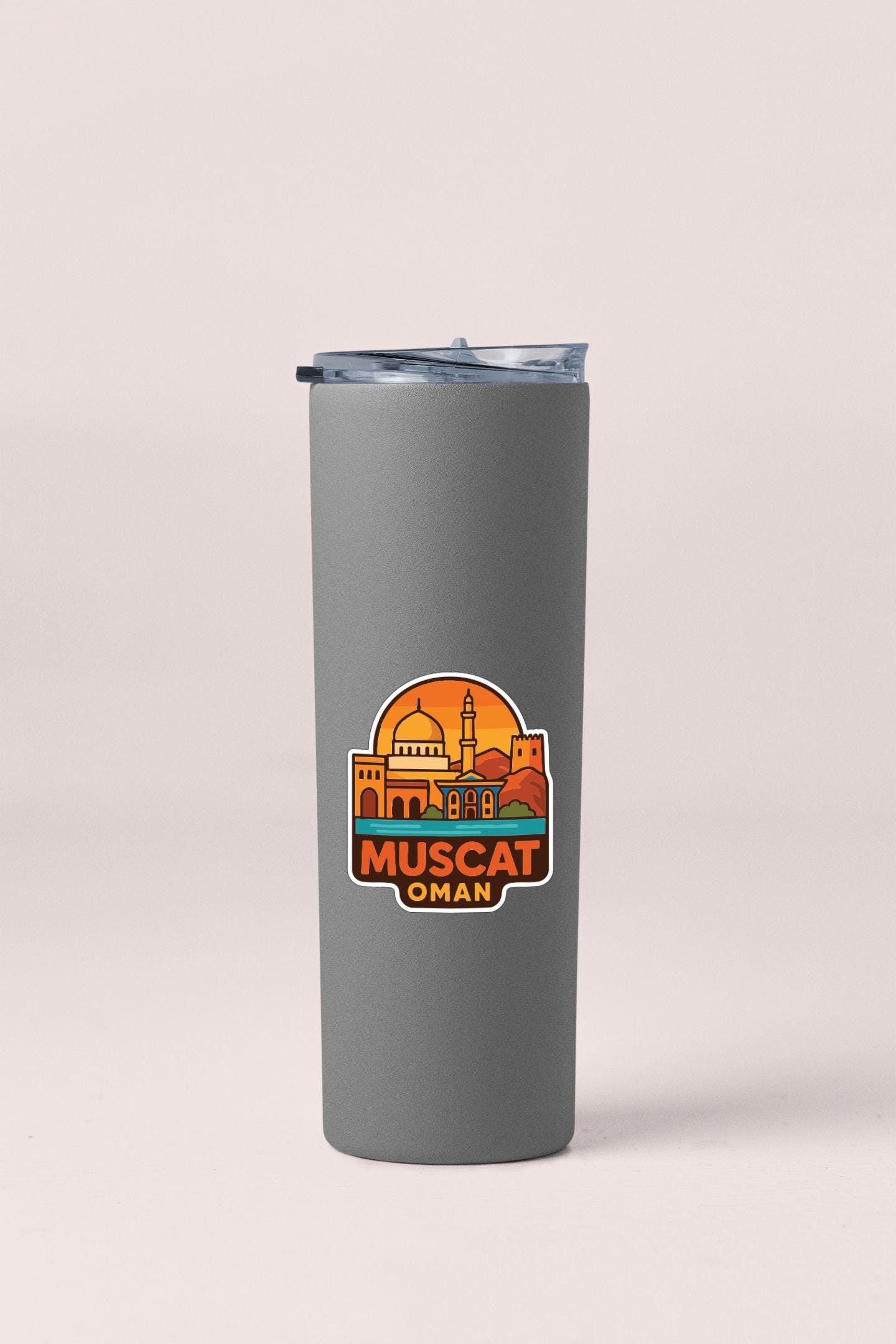 A gray insulated tumbler with a sticker depicting the city of Muscat, Oman.