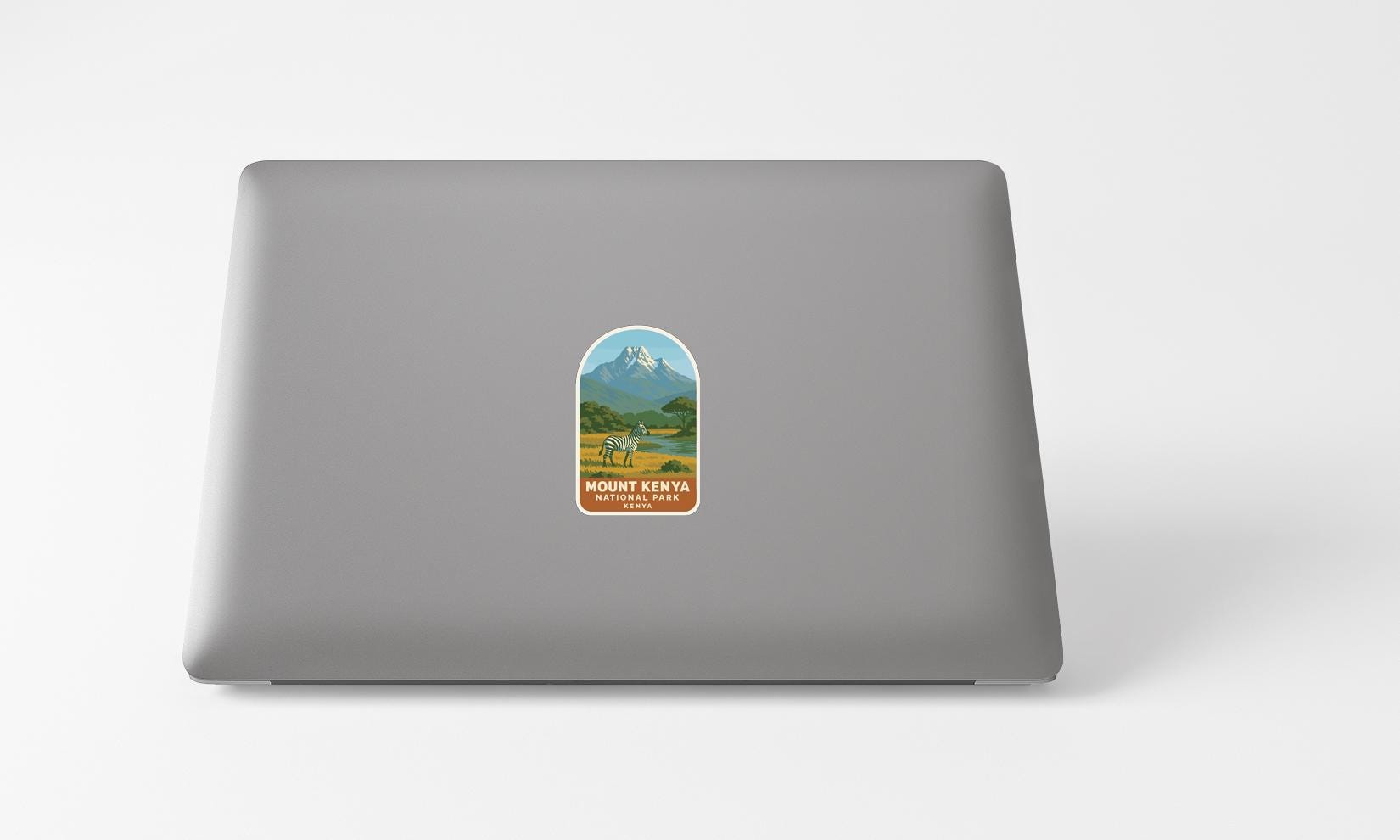 A sticker on the back of a laptop, depicting a mountain landscape with a mountain peak and a valley below.