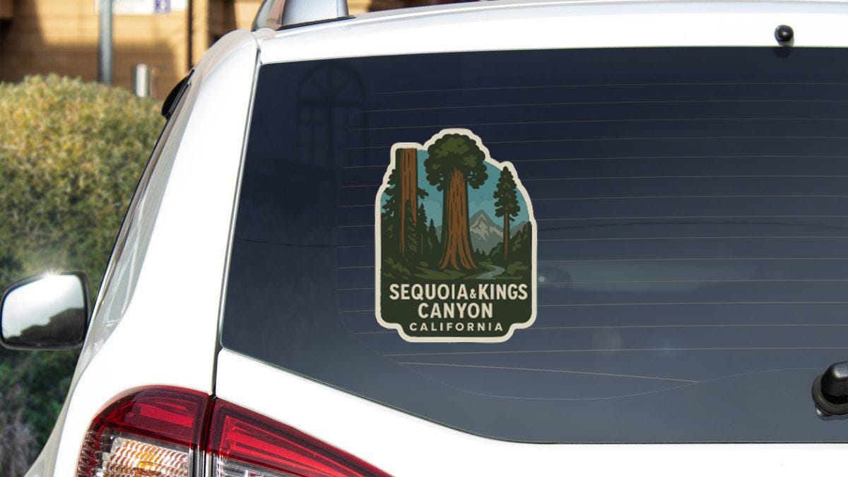 a sticker on the rear window of a white car, depicting a scenic view of Sequoia & Kings Canyon, California.