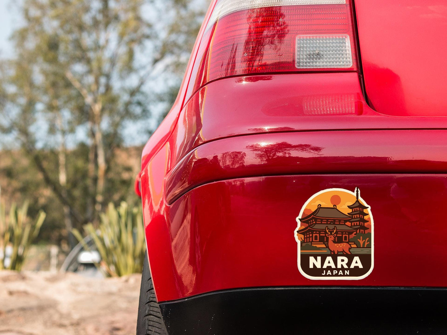 the rear end of a red car with a sticker on the back window that says "NARA JAPAN".