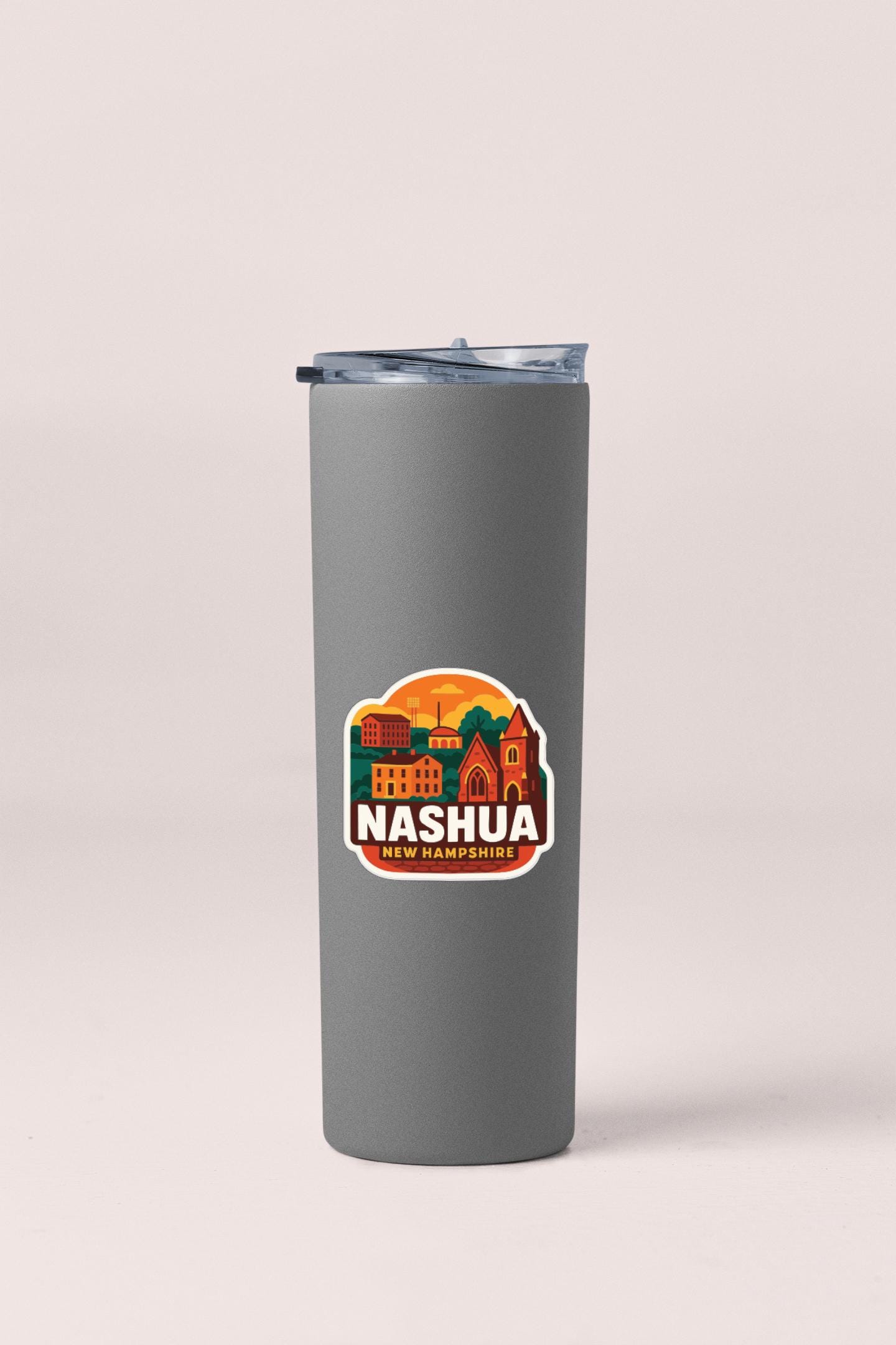 A gray insulated tumbler with a sticker depicting the city of Nashua, New Hampshire.