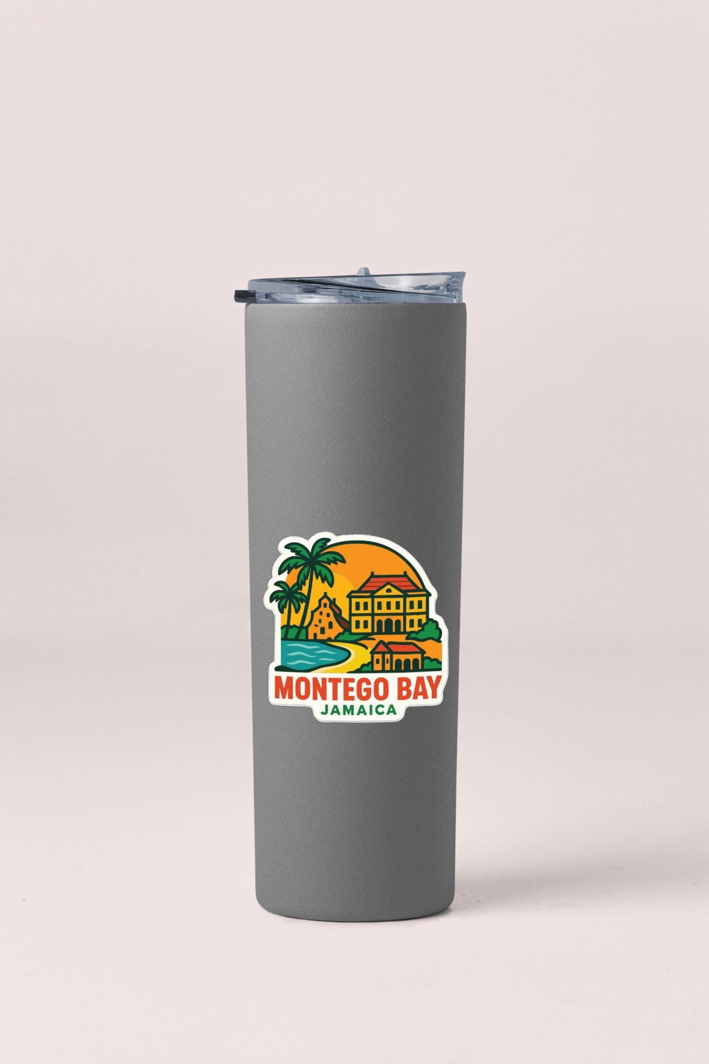 A gray insulated tumbler with a tropical island and palm tree design on it, featuring the text "MONTEGO BAY JAMAICA".