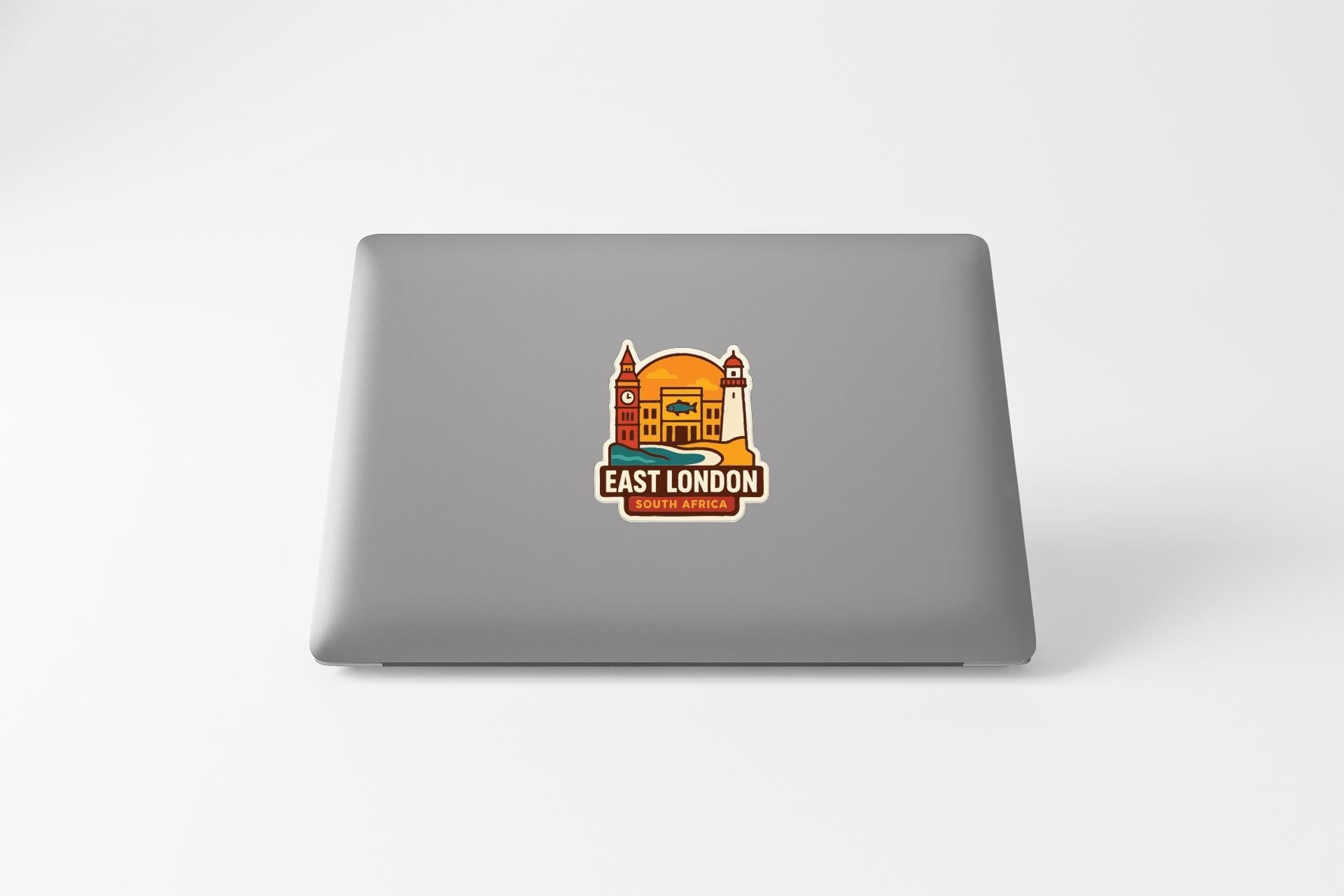 a sticker with a cartoon-style illustration of a building and the text "EAST LONDON" and "BRUSSELS, AFRICA" on the back of a laptop.